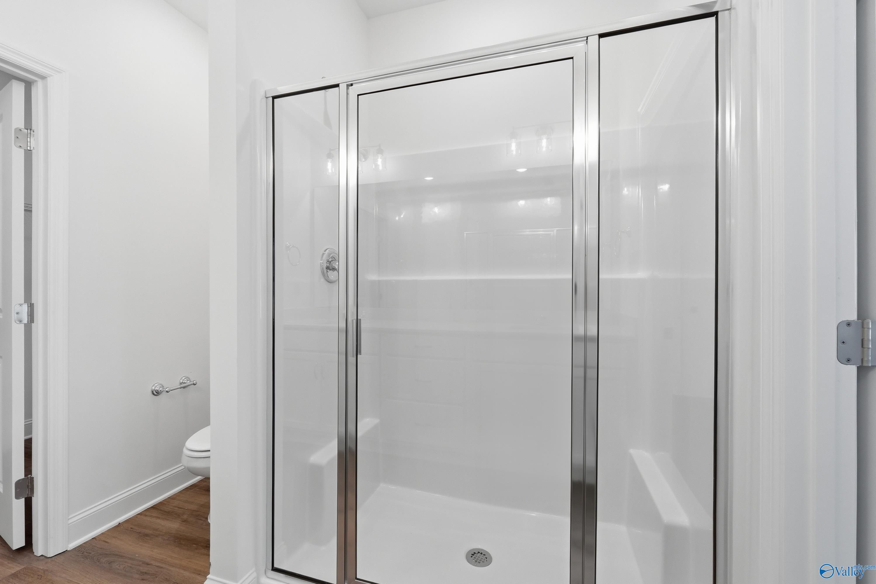 Modern frameless glass shower with white subway tiles and adjacent toilet in master bath of Davidson Homes The Cumberland D, Decatur, AL