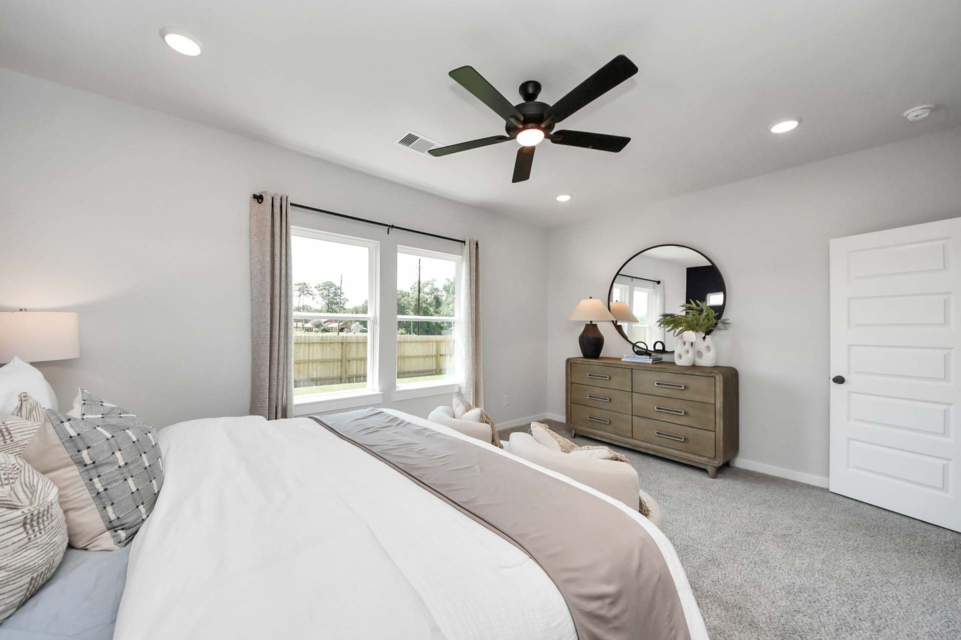 Spacious primary bedroom at Enclave at Newport in Crosby, TX by Davidson Homes featuring a modern dresser and ceiling fan.