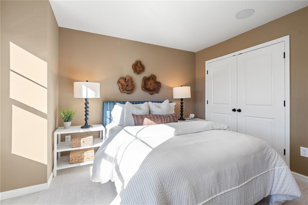 Cozy secondary bedroom with beige walls, wooden wall art, tufted bed, lamps in Davidson Homes The Marion B, Kennesaw, GA