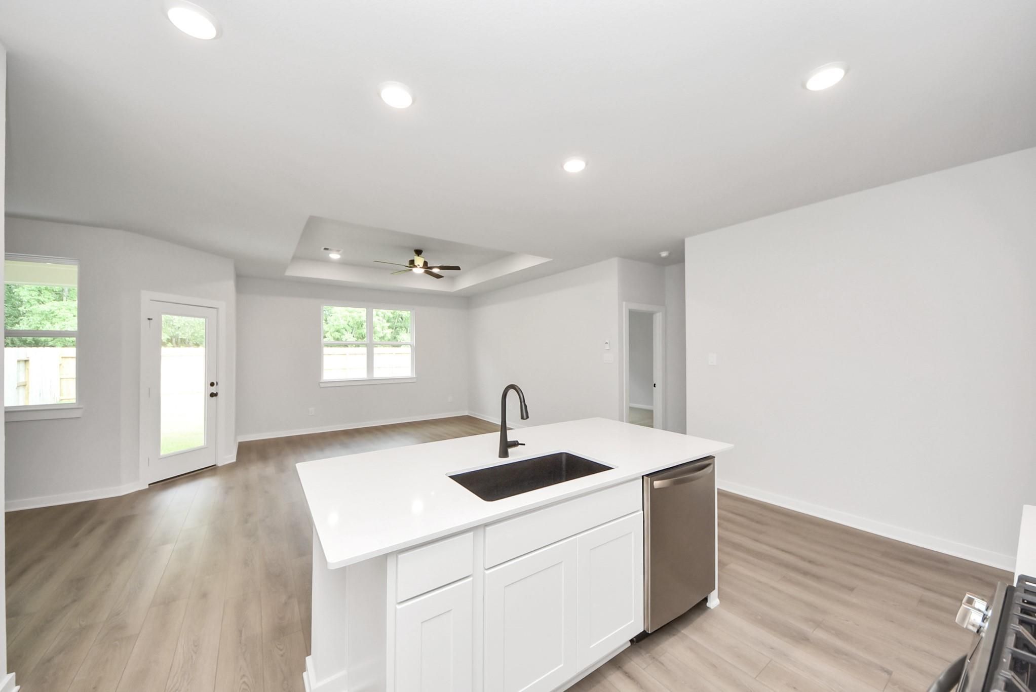 Modern kitchen island with quartz countertops and open-concept living area in The Daphne F floor plan, Crosby, Texas.