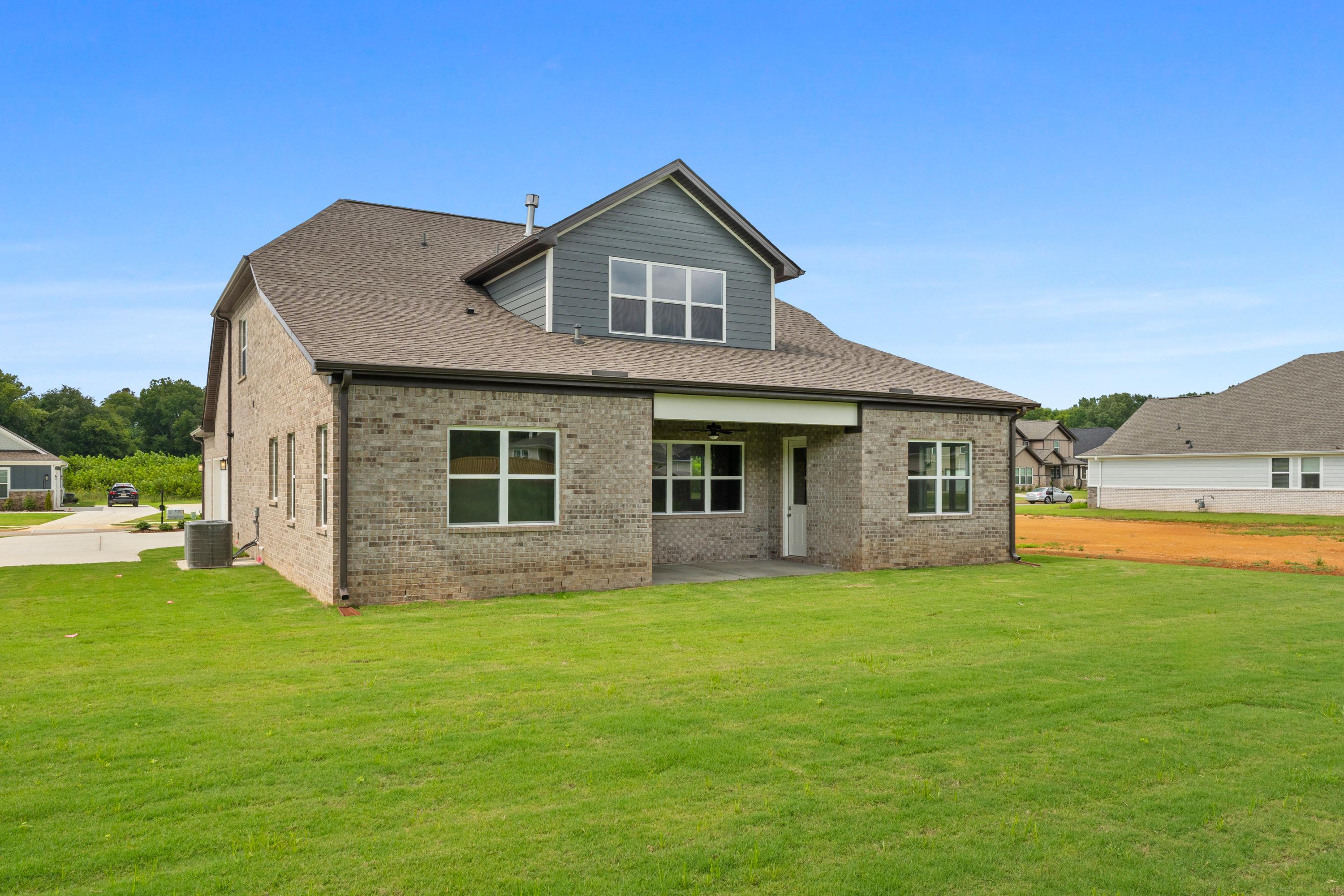 Two-story brick exterior of The Oxford C showcasing gray siding, covered porch, and 3-car garage on lush green lawn