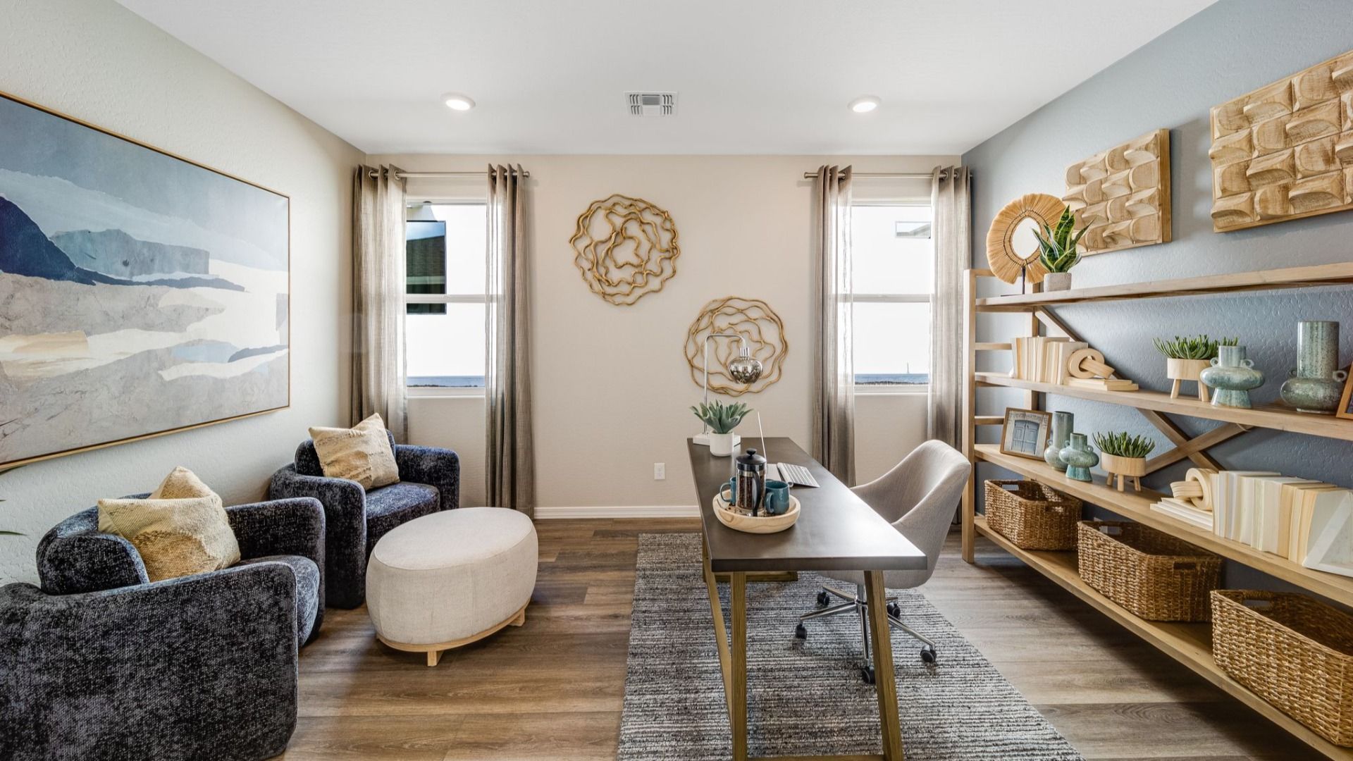 Stylish home office at Vineyards at Cottonwood in Cottonwood AZ featuring wooden shelves, abstract art, plush armchairs, ergonomic desk, and hardwood floors