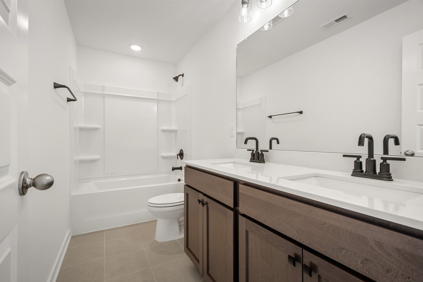 Elegant double vanity bathroom with soaking tub, black faucets, and tiled shower in Davidson Homes The Logan C, Gallatin, TN