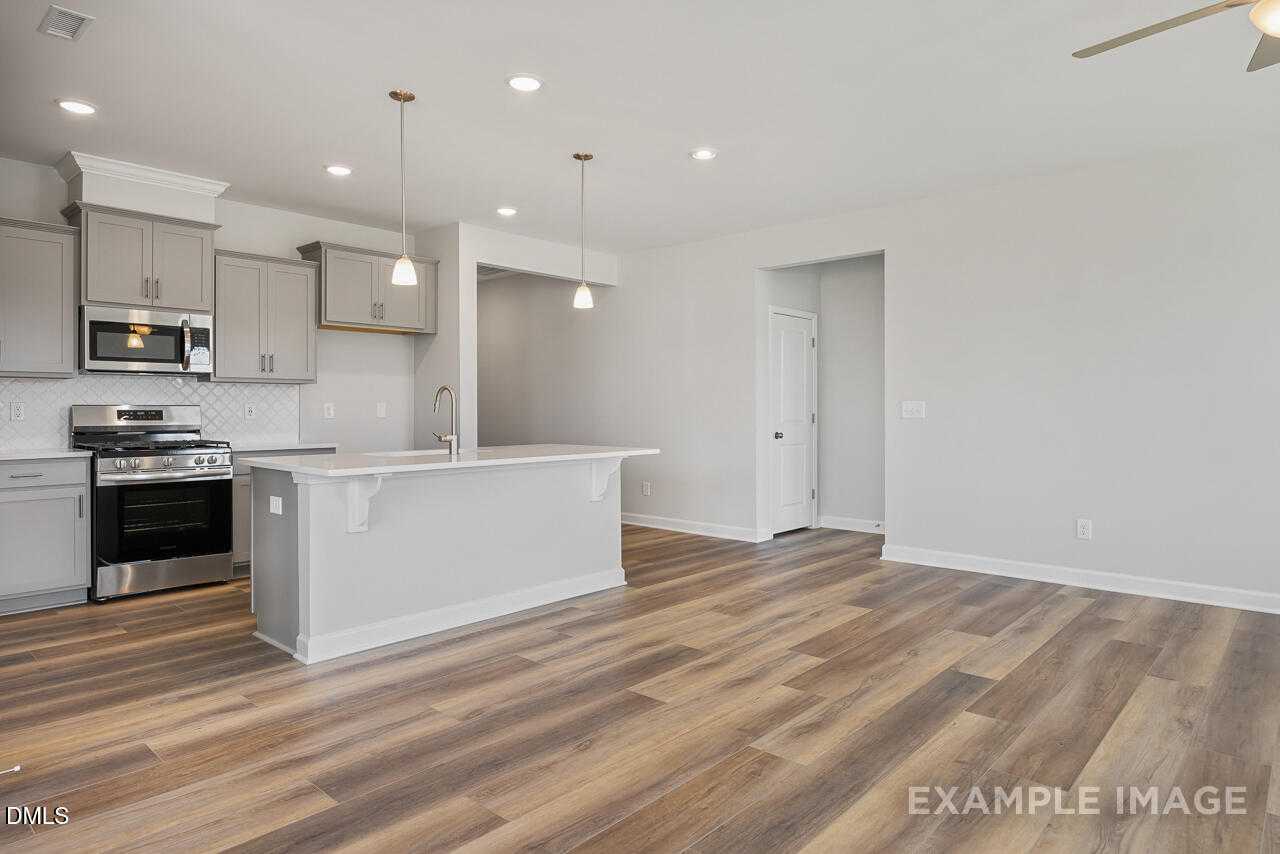 Modern white kitchen with stainless appliances, subway tile backsplash, and island in The Daphne C by Davidson Homes, Lillington, NC