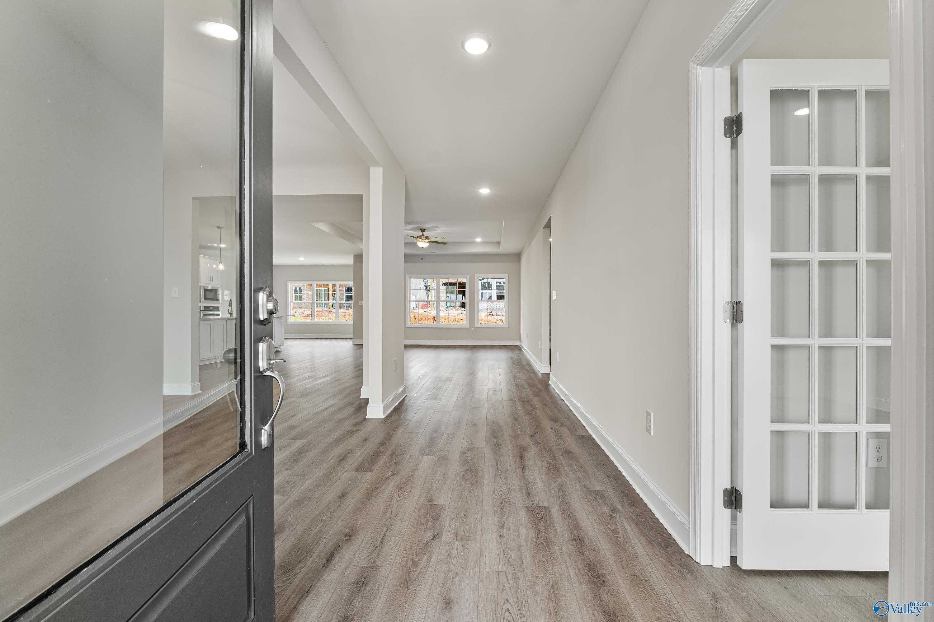 Bright entry hallway with luxury vinyl plank floors, large windows, and open layout in The Finleigh 3-bedroom home, Toney, Alabama