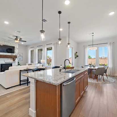 Open-concept kitchen and living room at Lago Mar in Texas City TX with stone fireplace, hardwood floors, granite island