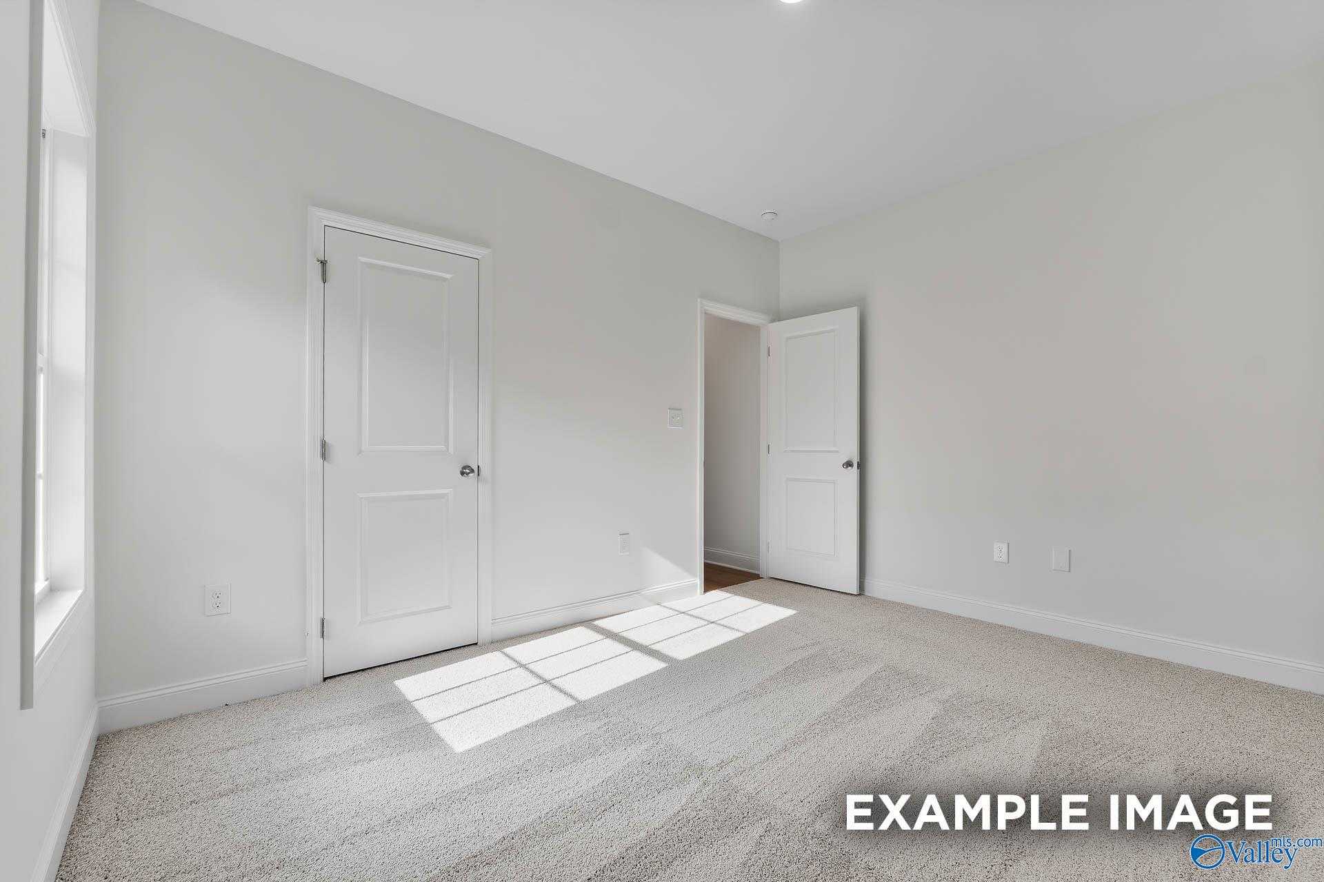Bright empty bedroom with sunlight streaming through window, white doors, and neutral carpet in 4-bedroom Davidson Homes The Daphne V, Athens, Alabama