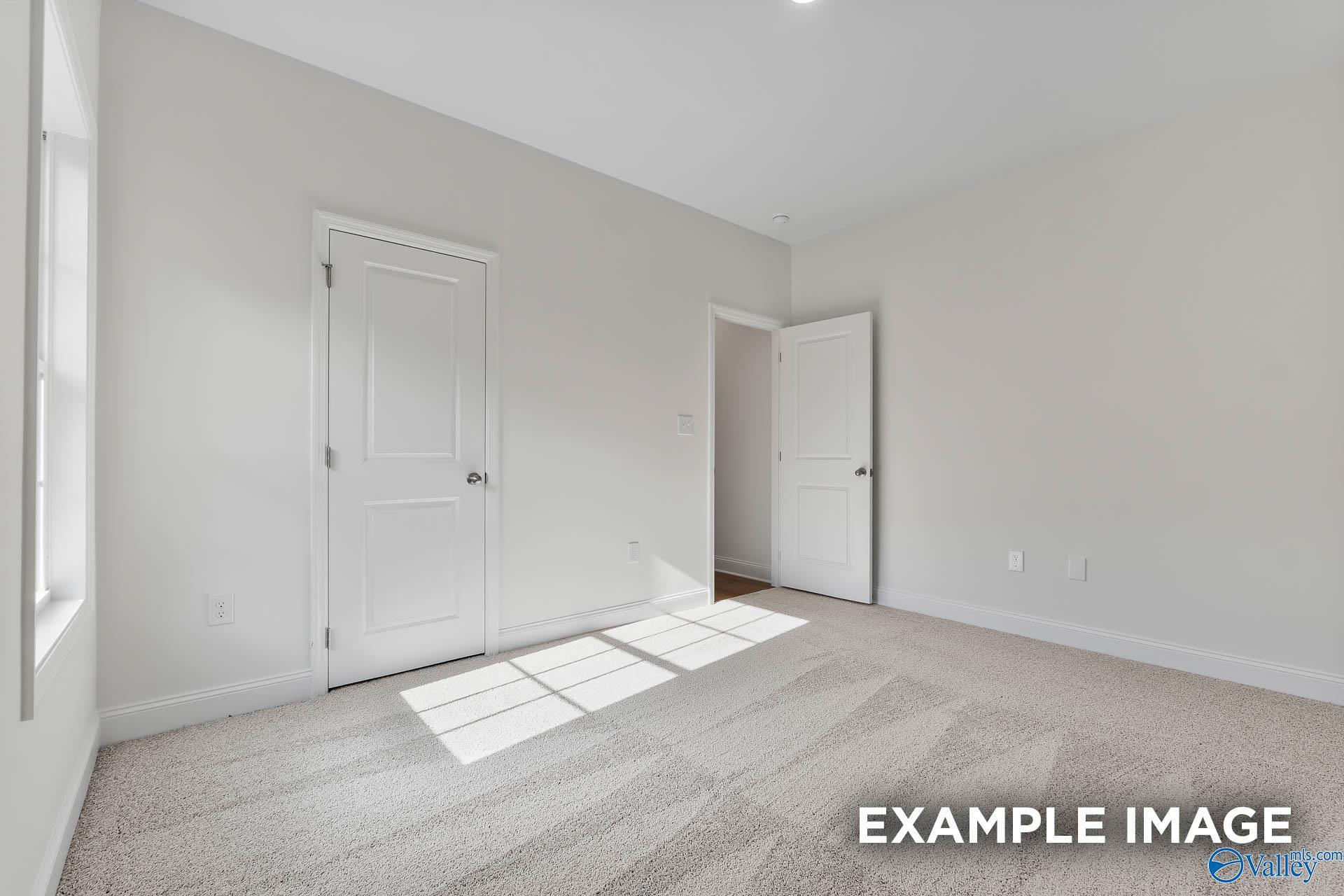 Bright empty bedroom with sunlight streaming through window, white doors, and neutral carpet in 4-bedroom Davidson Homes The Daphne V, Athens, Alabama