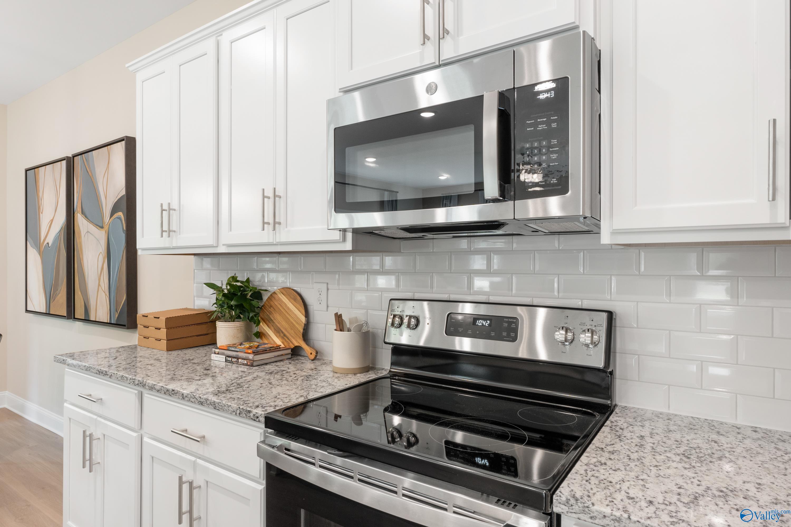 Modern kitchen featuring white shaker cabinets, granite countertops, stainless steel microwave and oven in Davidson Homes The Camden, Huntsville AL