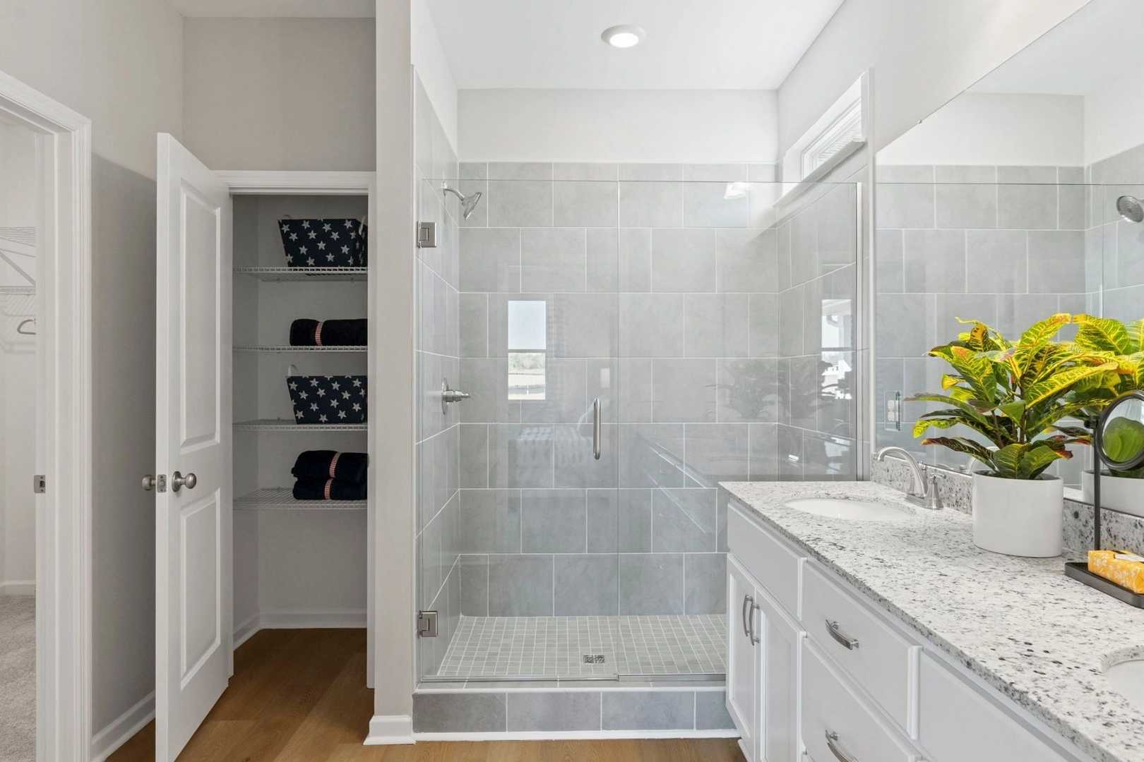 Modern bathroom at Bailey Park in Fayetteville TN with glass walk-in shower, double quartz vanity, and linen closet