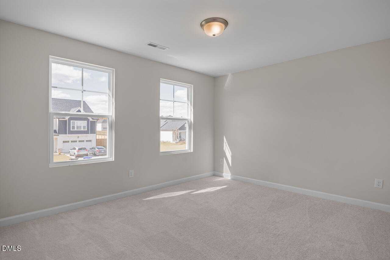 Bright secondary bedroom with double windows, neutral walls, and carpet in Davidson Homes The Gavin C, Lillington, NC