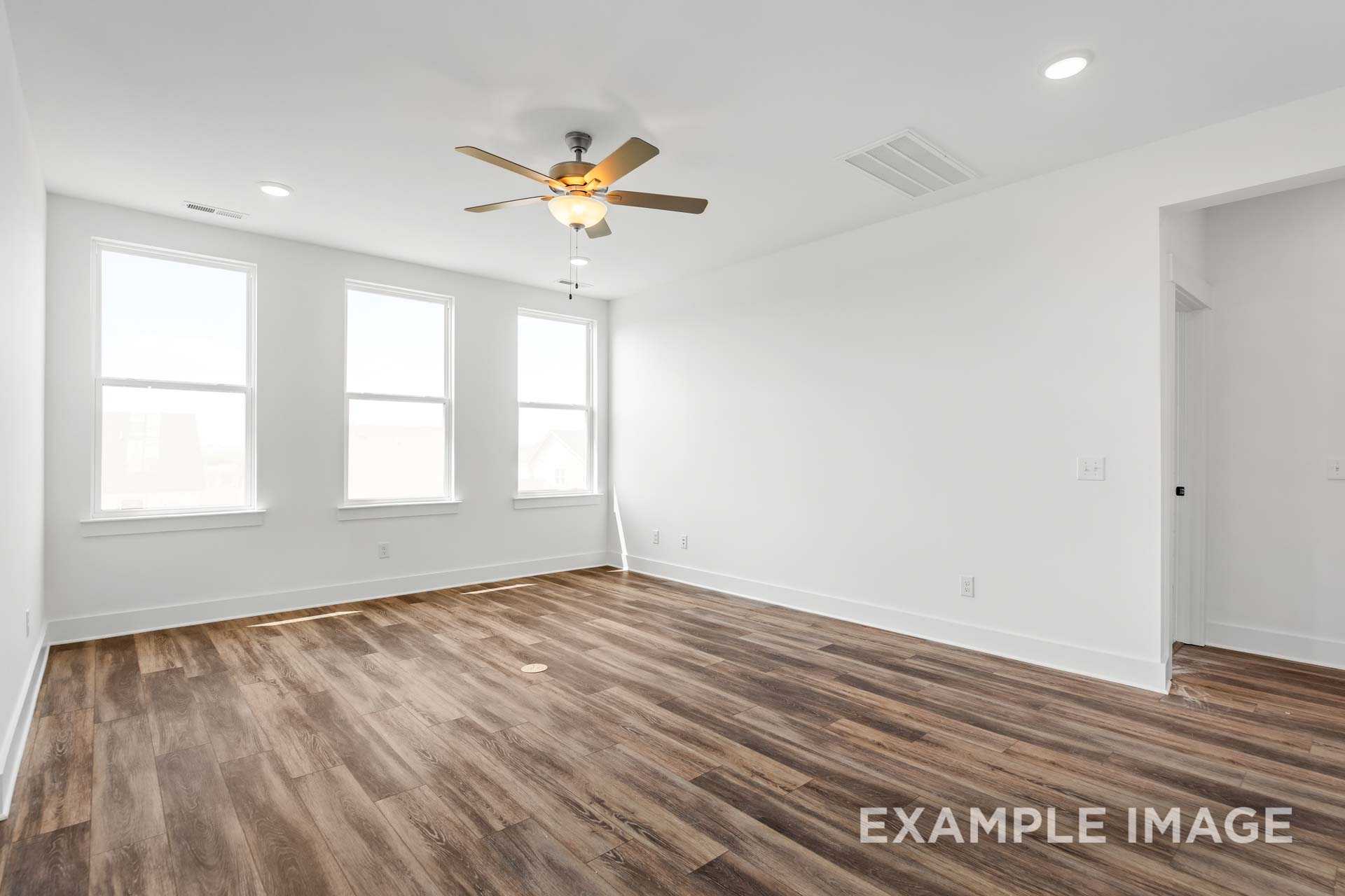 Spacious living room in The Ash Davidson Homes plan featuring hardwood floors, large windows, and ceiling fan in Mt. Juliet TN