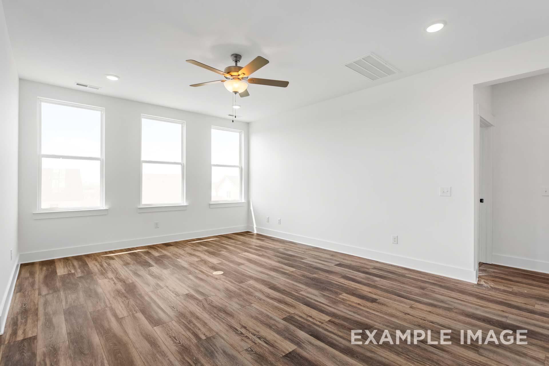Spacious living room in The Ash Davidson Homes plan featuring hardwood floors, large windows, and ceiling fan in Mt. Juliet TN