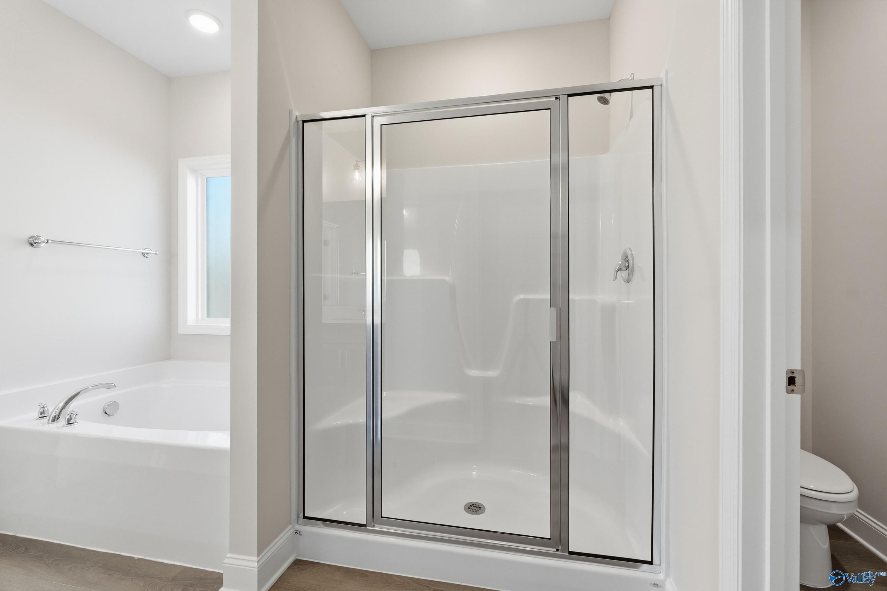 Modern master bathroom featuring glass-enclosed shower and jetted tub in Davidson Homes The Daphne C, Arab, Alabama