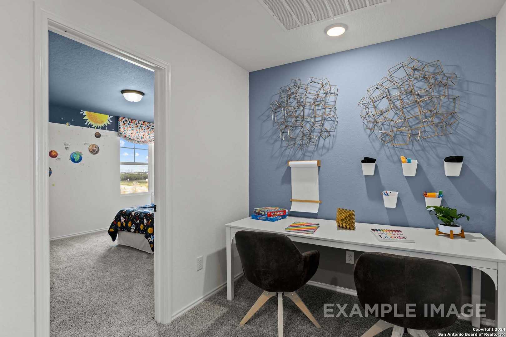 Space-themed kids' bedroom with study desk, blue walls, and metal art in Davidson Homes The Douglas G, Bricewood, San Antonio
