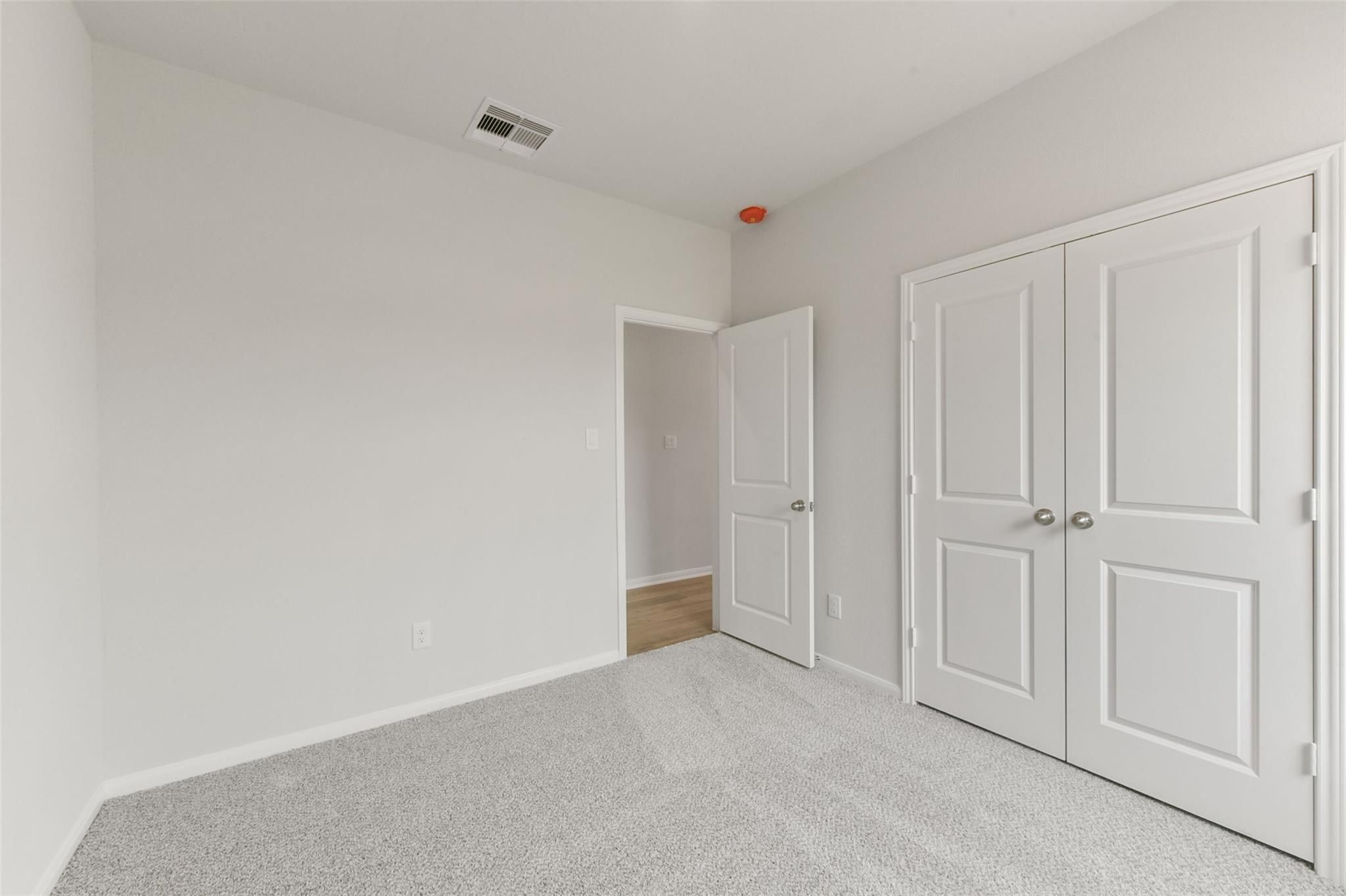 Spacious bedroom with gray carpet, white walls, double closet doors in Davidson Homes The Laguna B, Magnolia, Texas