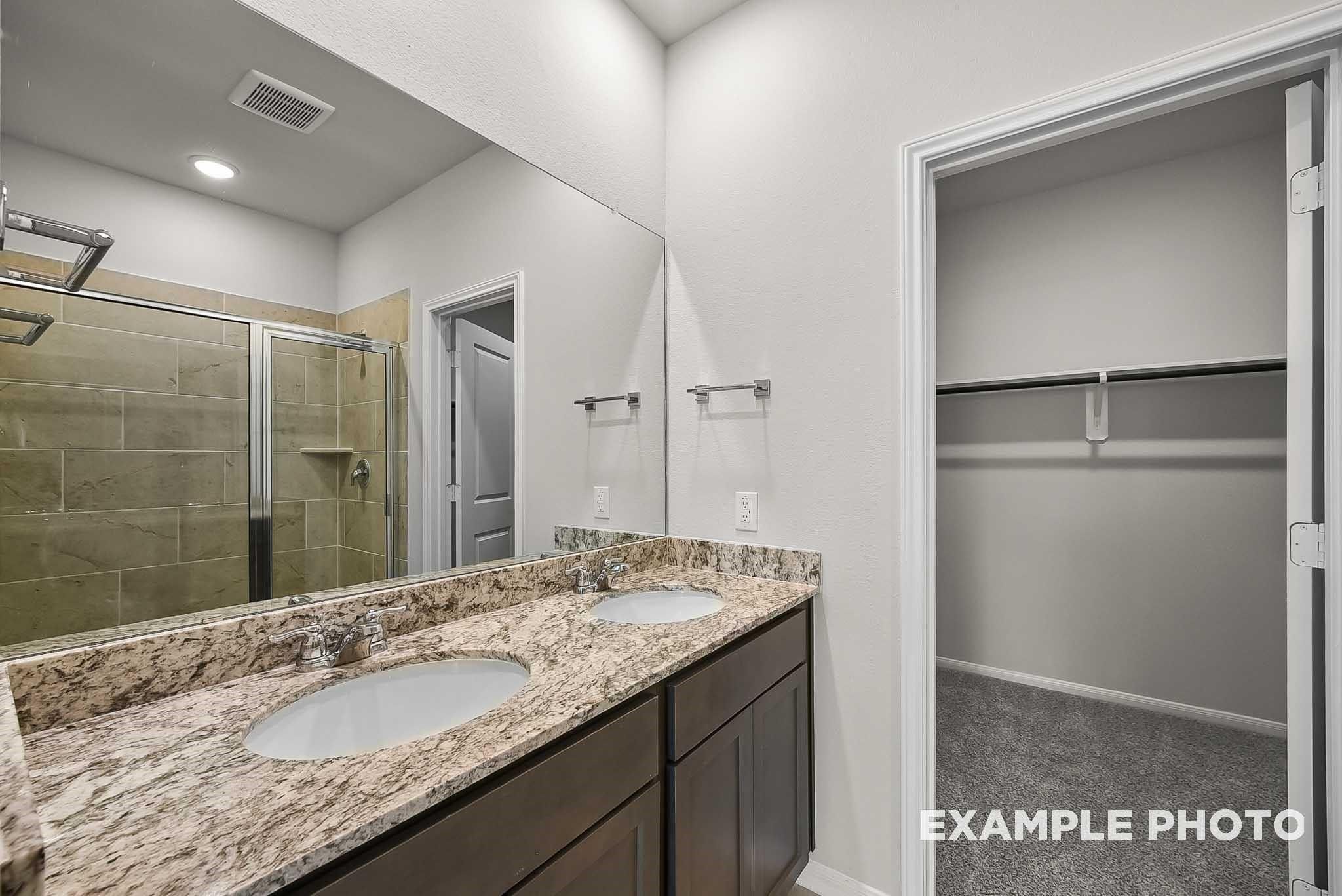 Double vanity bathroom with granite countertops and walk-in closet in The Blanco F floor plan at Spring Branch Crossing.
