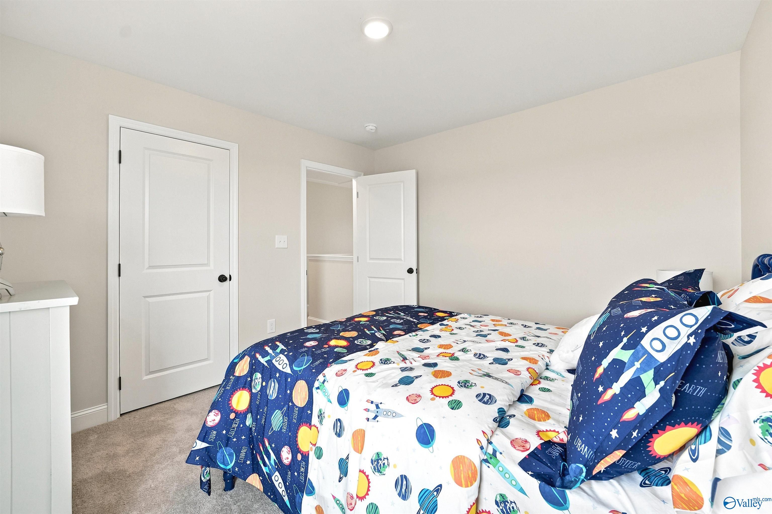 Spacious secondary bedroom with space-themed bedding in The Burton B floor plan at Heritage Lakes, New Market, Alabama.