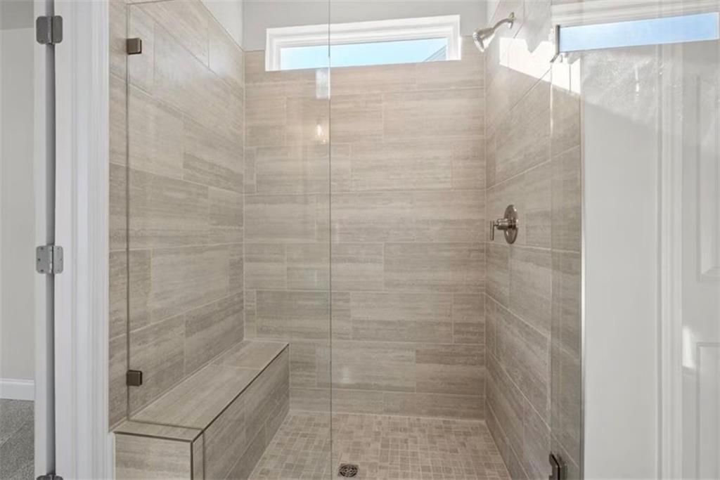 Walk-in tiled shower with built-in bench in The Ash C floor plan at Wehunt Meadows, Hoschton, Georgia.