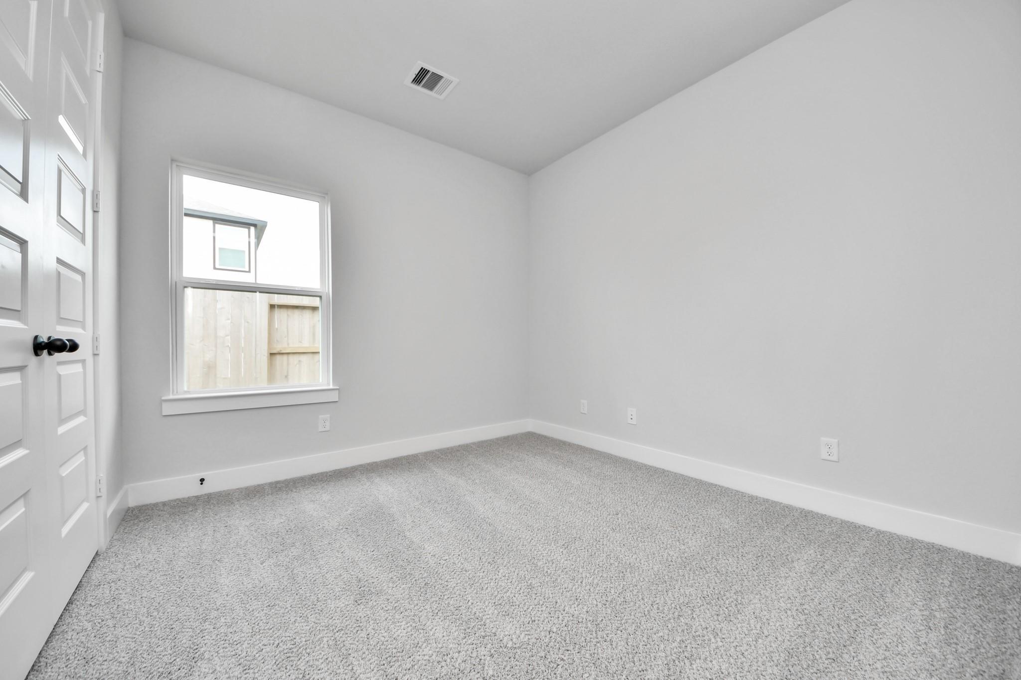 Bright, carpeted secondary bedroom in The Laguna C floor plan by Davidson Homes at Sunterra in Katy, Texas.