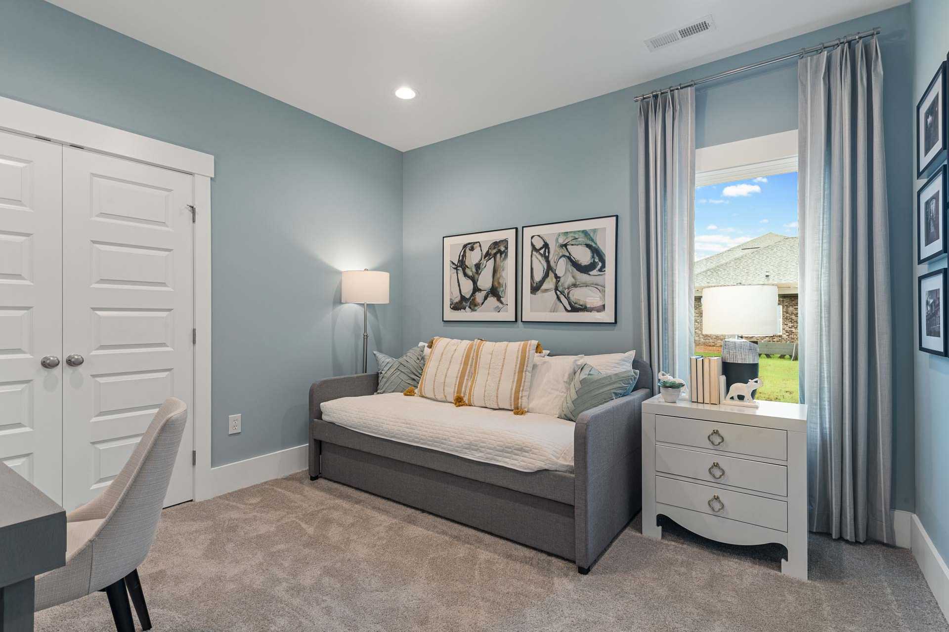 Cozy soft blue bedroom at Monteagle Cove in Owens Cross Roads Alabama with daybed, desk, abstract art and window view