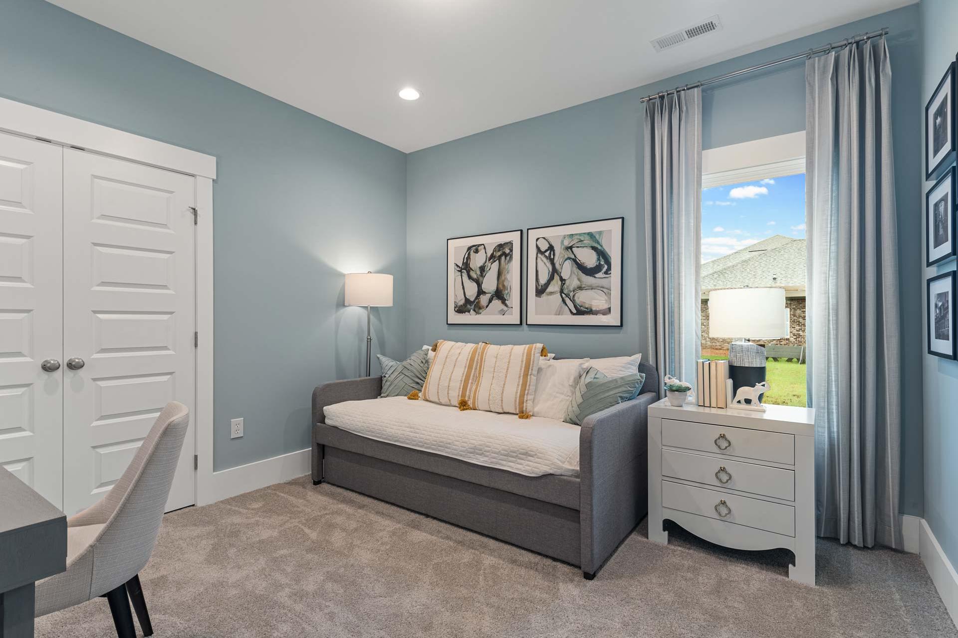 Cozy soft blue bedroom at Monteagle Cove in Owens Cross Roads Alabama with daybed, desk, abstract art and window view