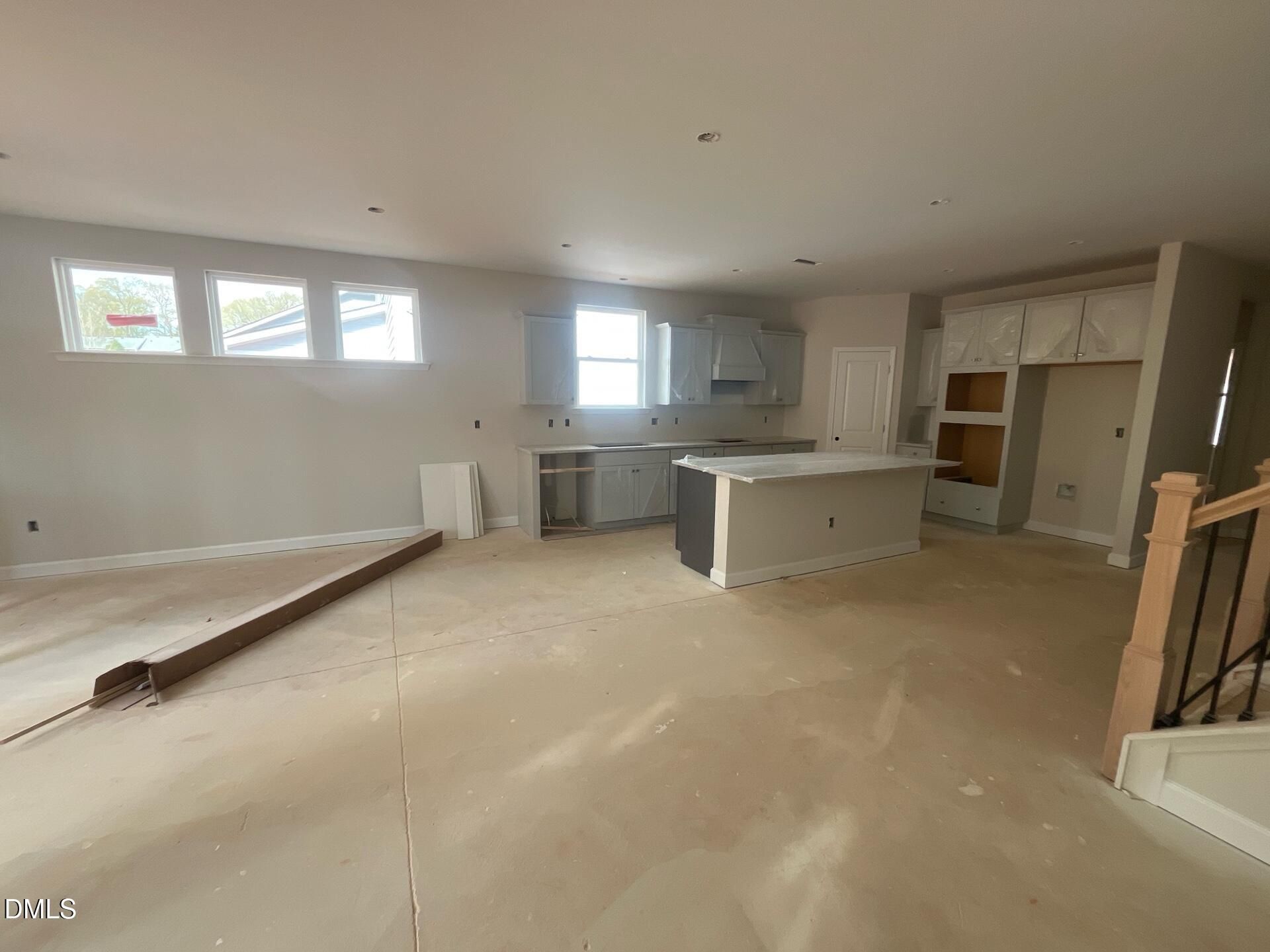 Spacious open-concept kitchen under construction with white cabinets, large island, and staircase in Davidson Homes Ashport G, Wake Forest, NC