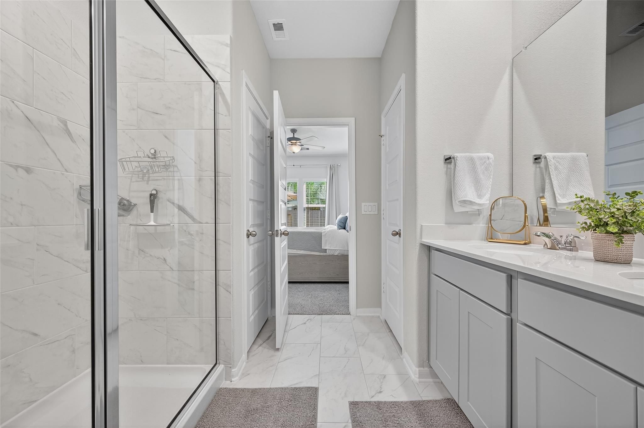 Modern master bathroom with frameless glass shower, double vanity, and bedroom access in Davidson Homes The Brazos E, Magnolia, Texas