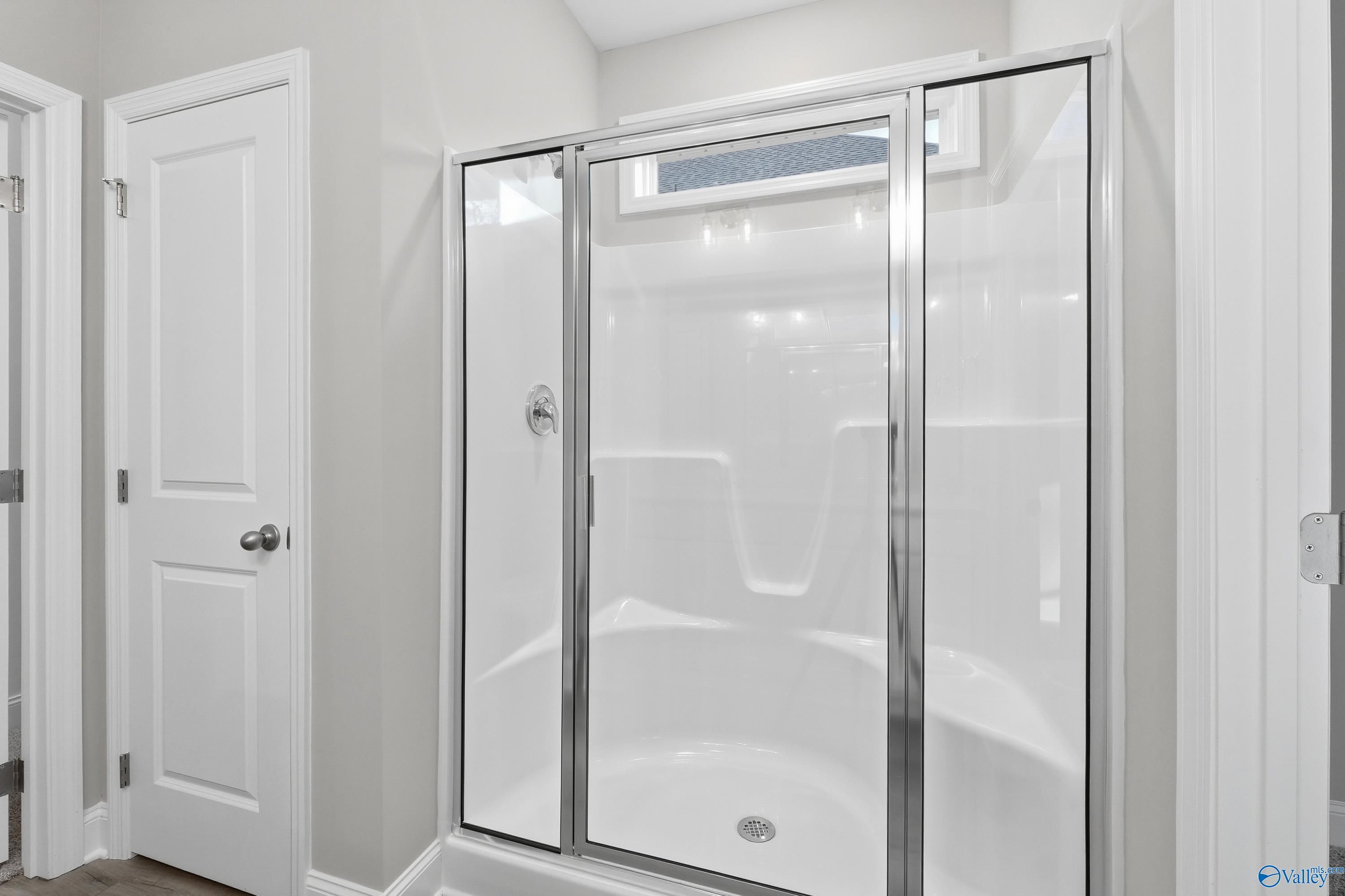 Modern frameless glass shower with white subway tiles in master bath of Davidson Homes The Asheville, Arab, Alabama