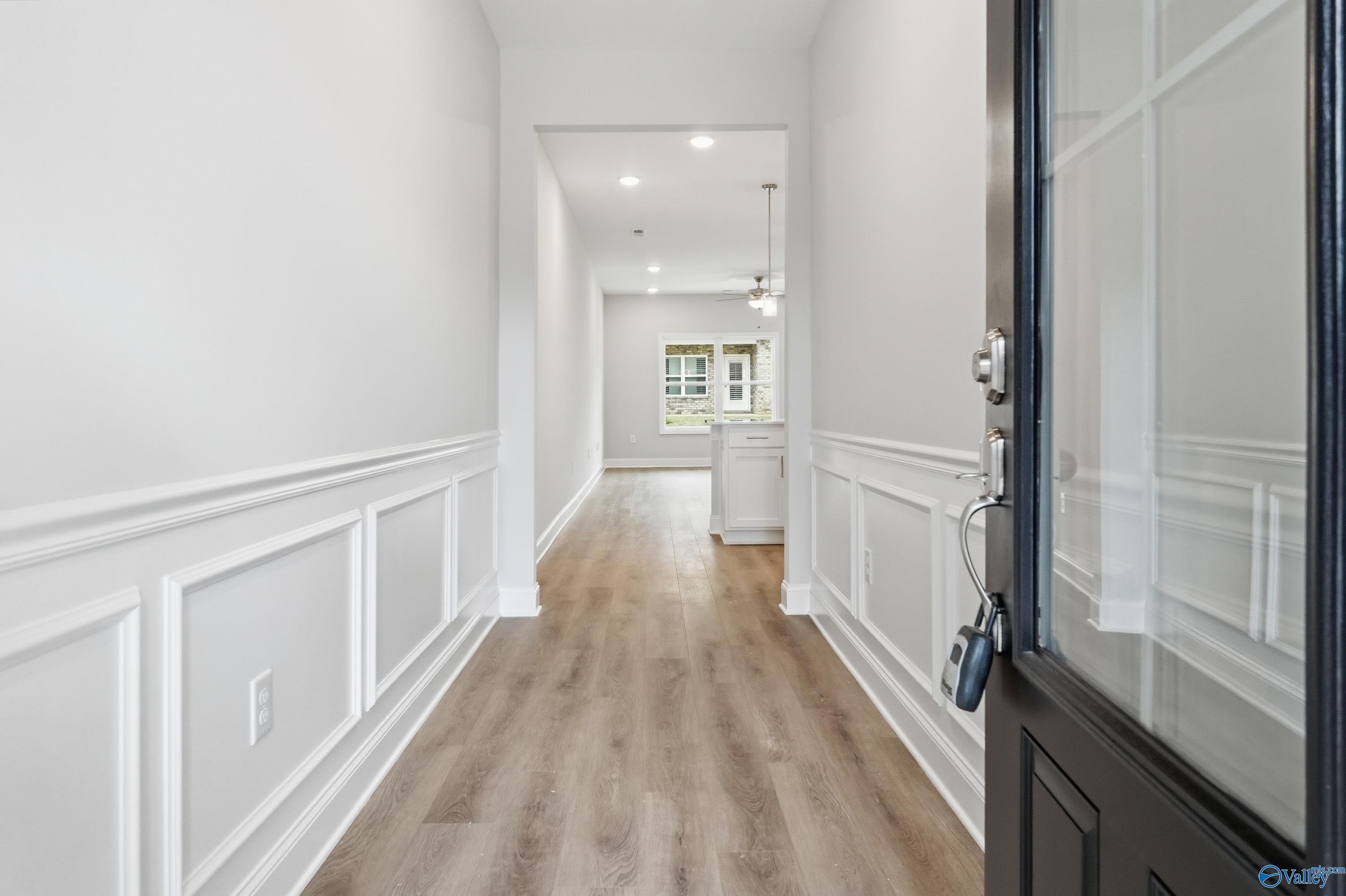 Elegant entry hallway with white wainscoting, hardwood floors, and open kitchen view in Davidson Homes The Cumberland, Decatur, Alabama