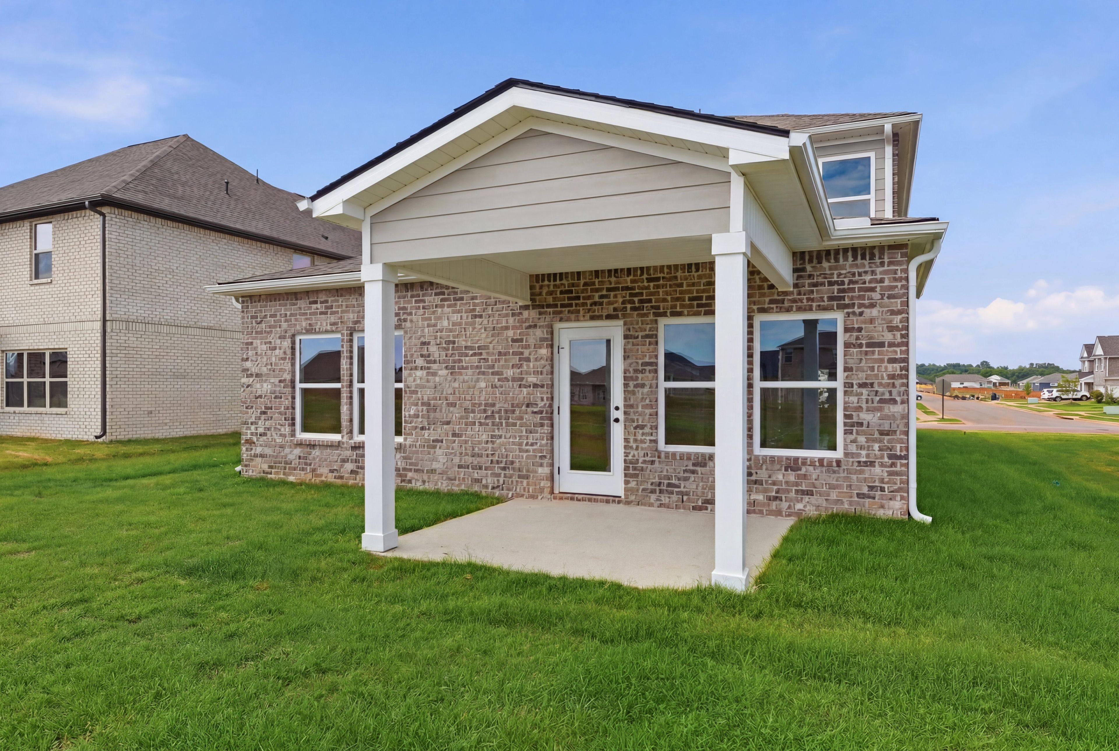 Covered rear patio of The Meadowbrook home design in Meridianville, featuring brick exterior and spacious backyard.