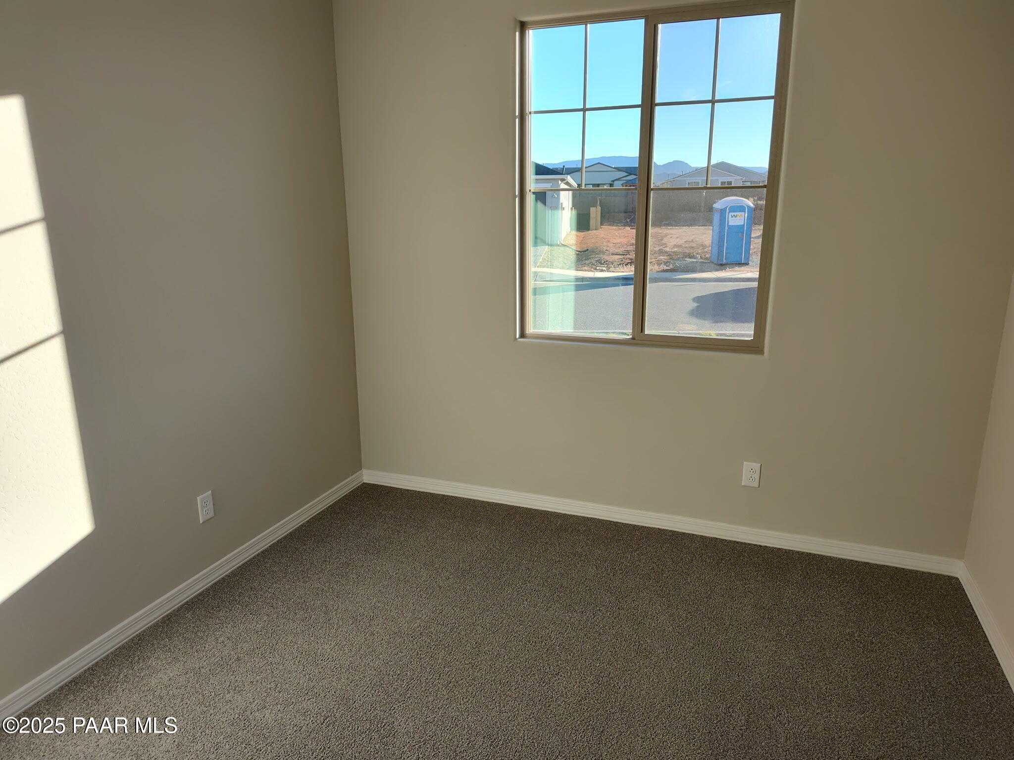 Bright secondary bedroom with neutral walls, carpeted floor, and large window showcasing Prescott Valley mountain views in Davidson Homes The Frontier A