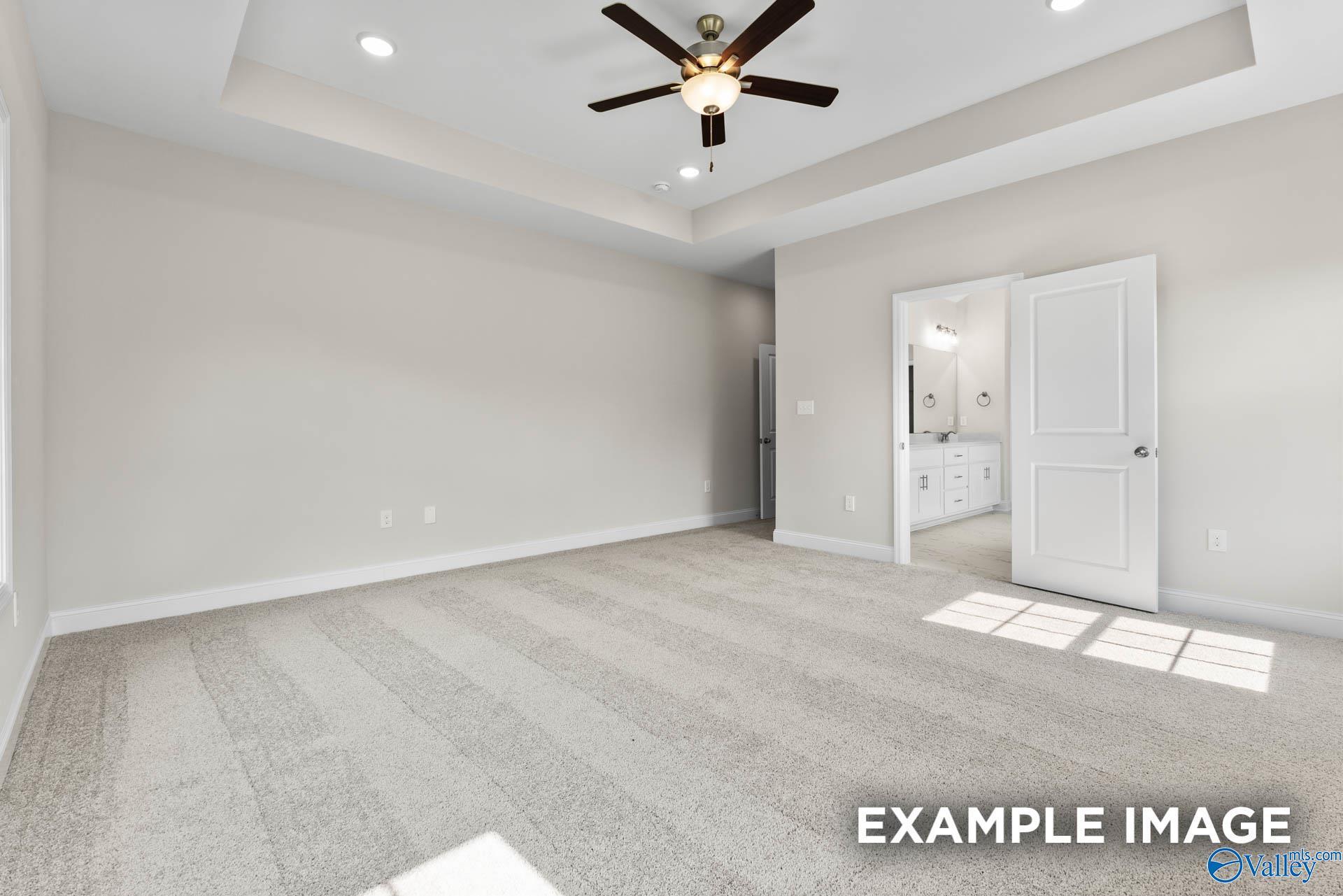 Bright master bedroom with ceiling fan, tray ceiling, and en-suite bathroom in Davidson Homes The Finleigh, Huntsville AL