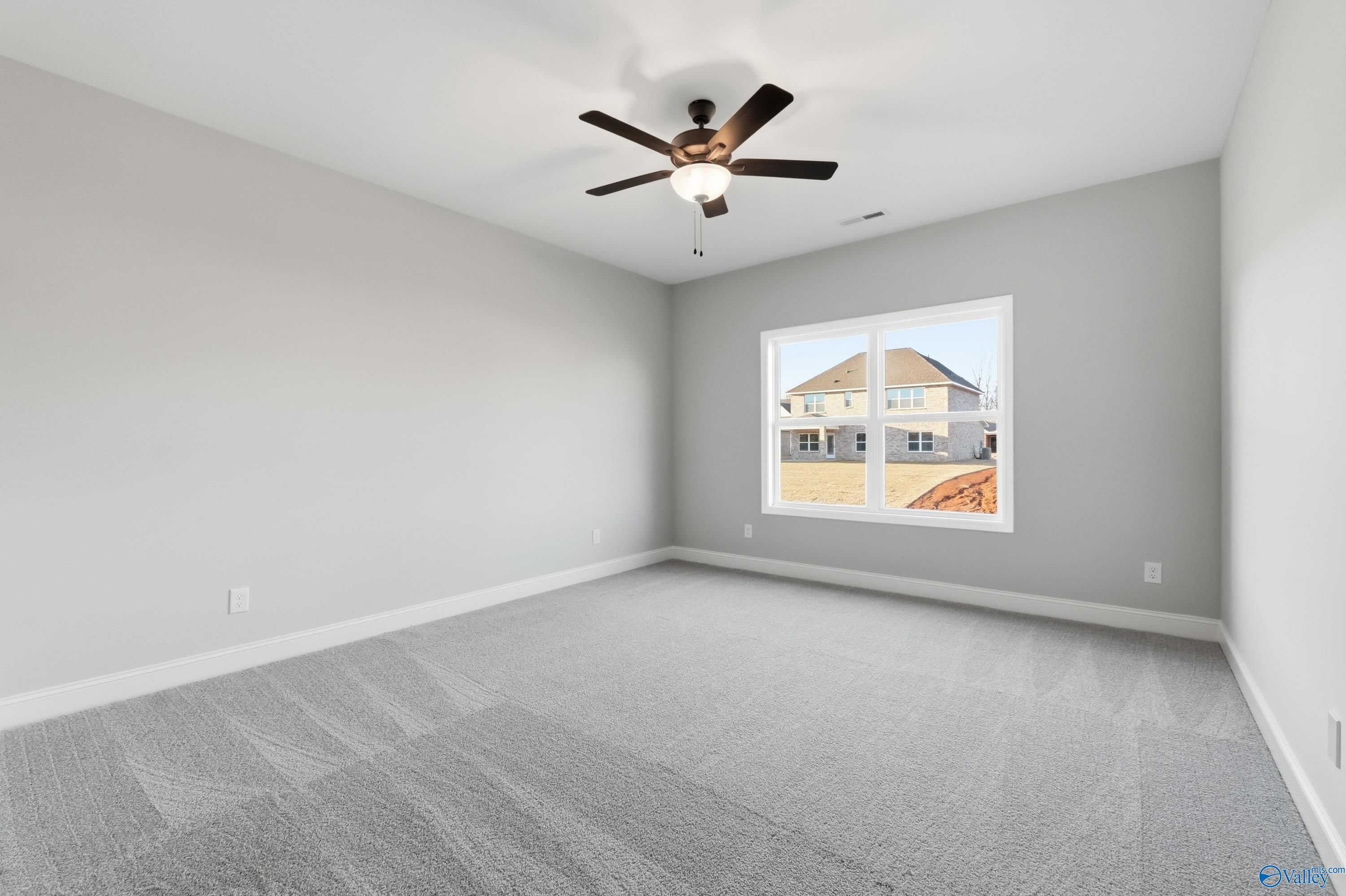 Spacious secondary bedroom with gray carpet, ceiling fan, and window view in Davidson Homes The Daphne C, Athens, Alabama