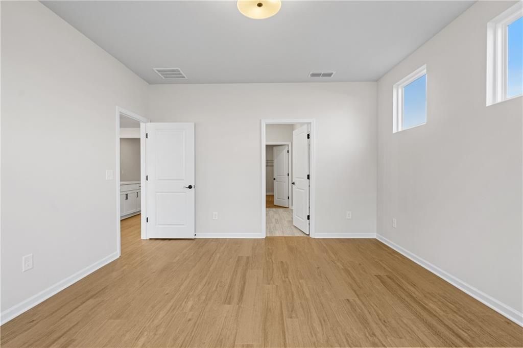 Spacious great room with hardwood floors, white walls, large windows, and open doorways in Davidson Homes The Edison B, Kelly Preserve, Loganville, GA