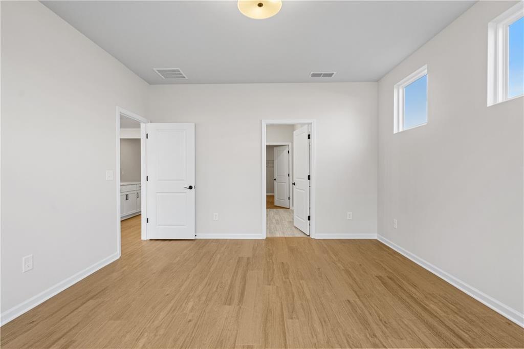 Spacious great room with hardwood floors, white walls, large windows, and open doorways in Davidson Homes The Edison B, Kelly Preserve, Loganville, GA