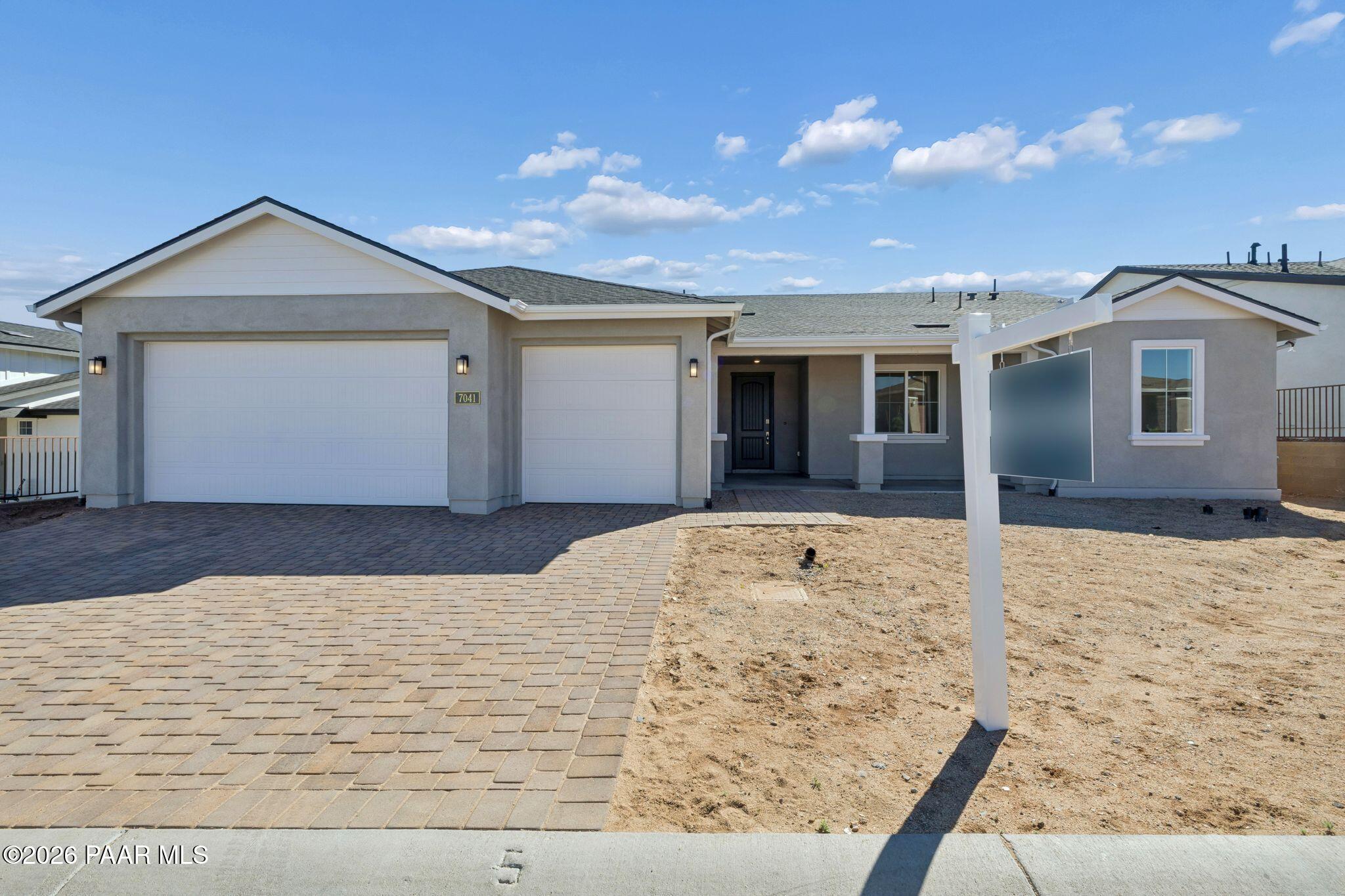 Single-story 3-car garage home exterior with modern stucco facade and for-sale sign in Westwood, Prescott, Arizona - Davidson Homes The Monarch A