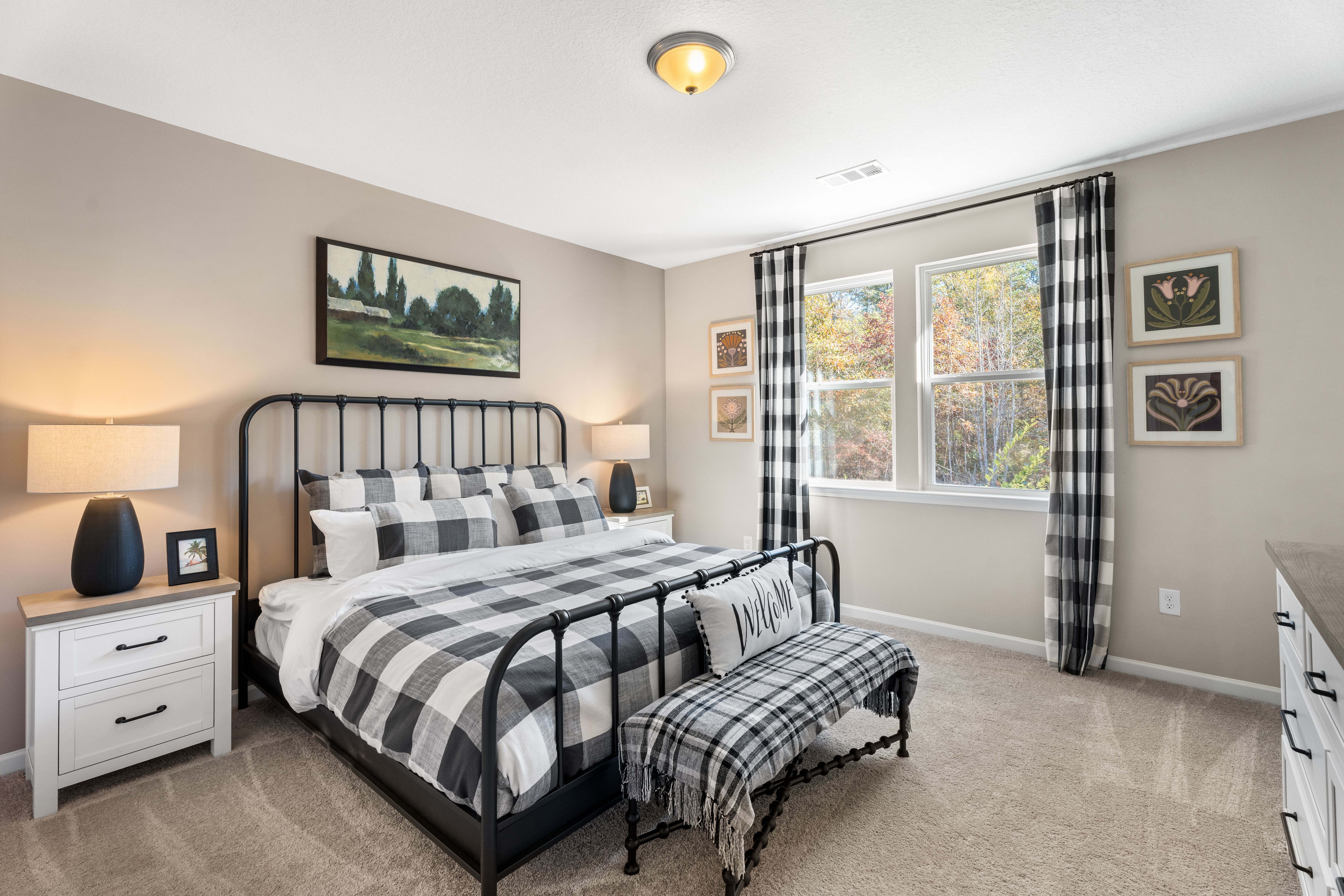 Spacious master bedroom at Silver Oak in Cusseta Alabama with black metal bed frame, checkered bedding, and neutral walls