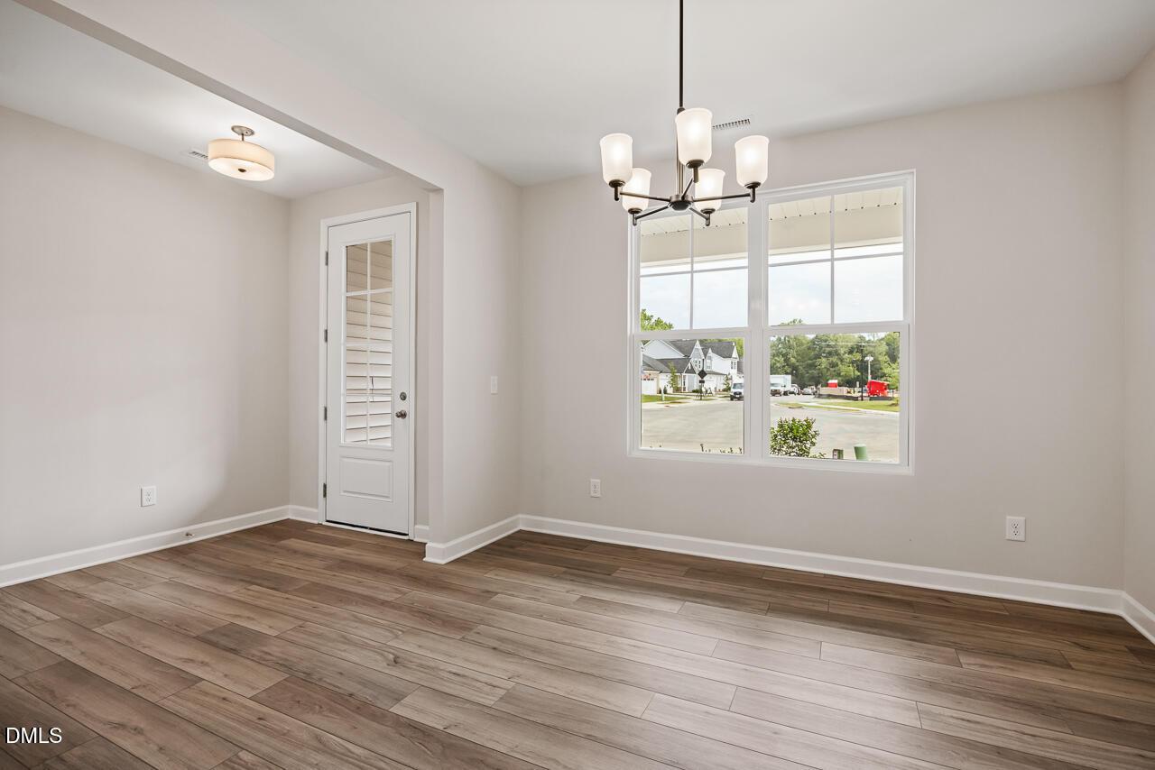 Bright dining area with modern chandelier and wood-look flooring in The Ash C floor plan at Woodland Crossing, Zebulon, NC.