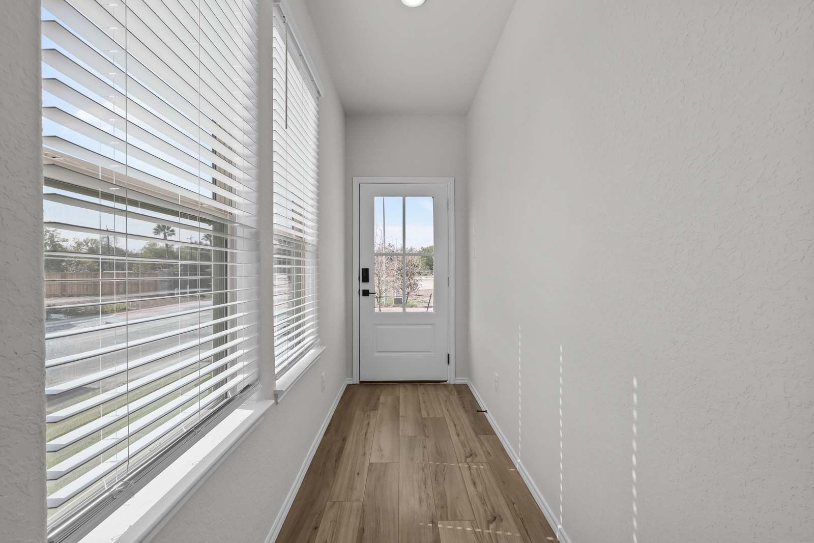 Bright entryway in The Florence B model home featuring wood-look flooring, large windows, and a glass-paneled exterior door.