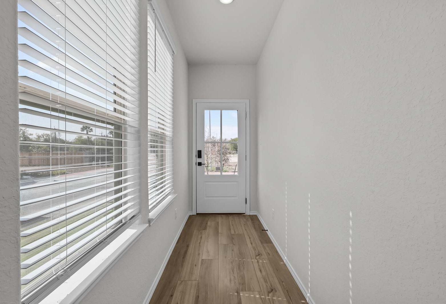 Bright entryway in The Florence B model home featuring wood-look flooring, large windows, and a glass-paneled exterior door.