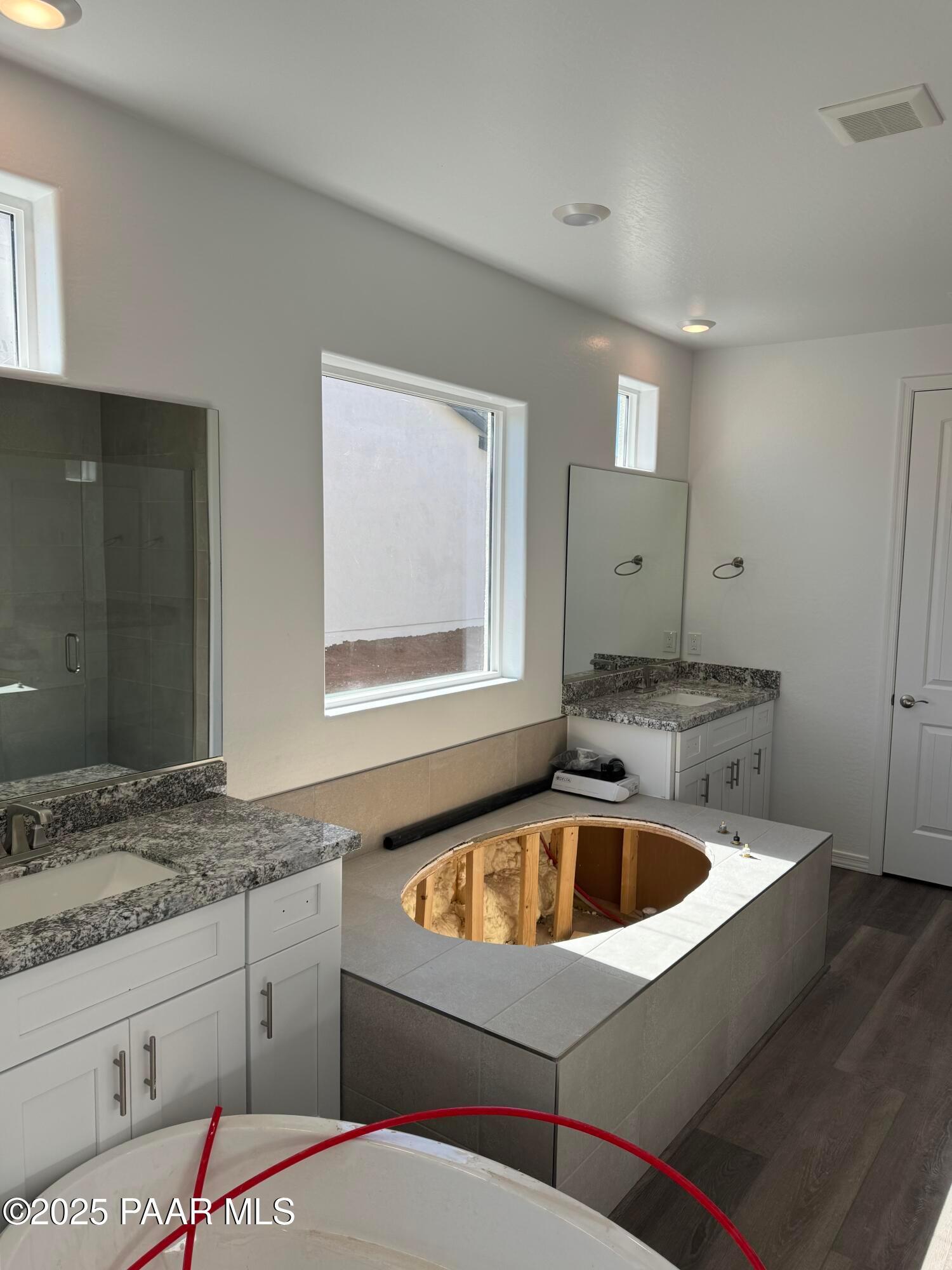 Modern master bathroom featuring double granite vanity, large window, and oval soaking tub in Davidson Homes Sunrise II A, Prescott AZ