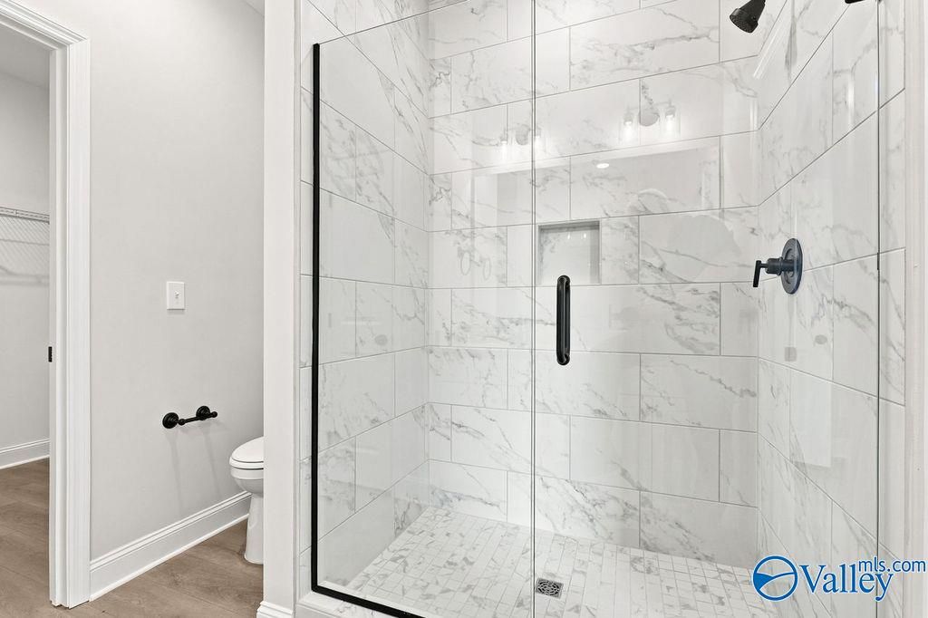 Walk-in glass shower with marble-style tile in The Camilla B floor plan at The Retreat at Cain Park, Hartselle, Alabama.