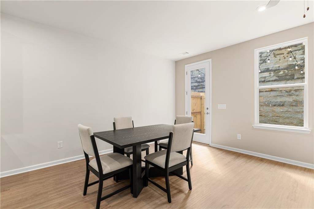 Contemporary dining room with black rectangular table, beige upholstered chairs, sliding glass door to backyard in Davidson Homes The Marion B, Kennesaw