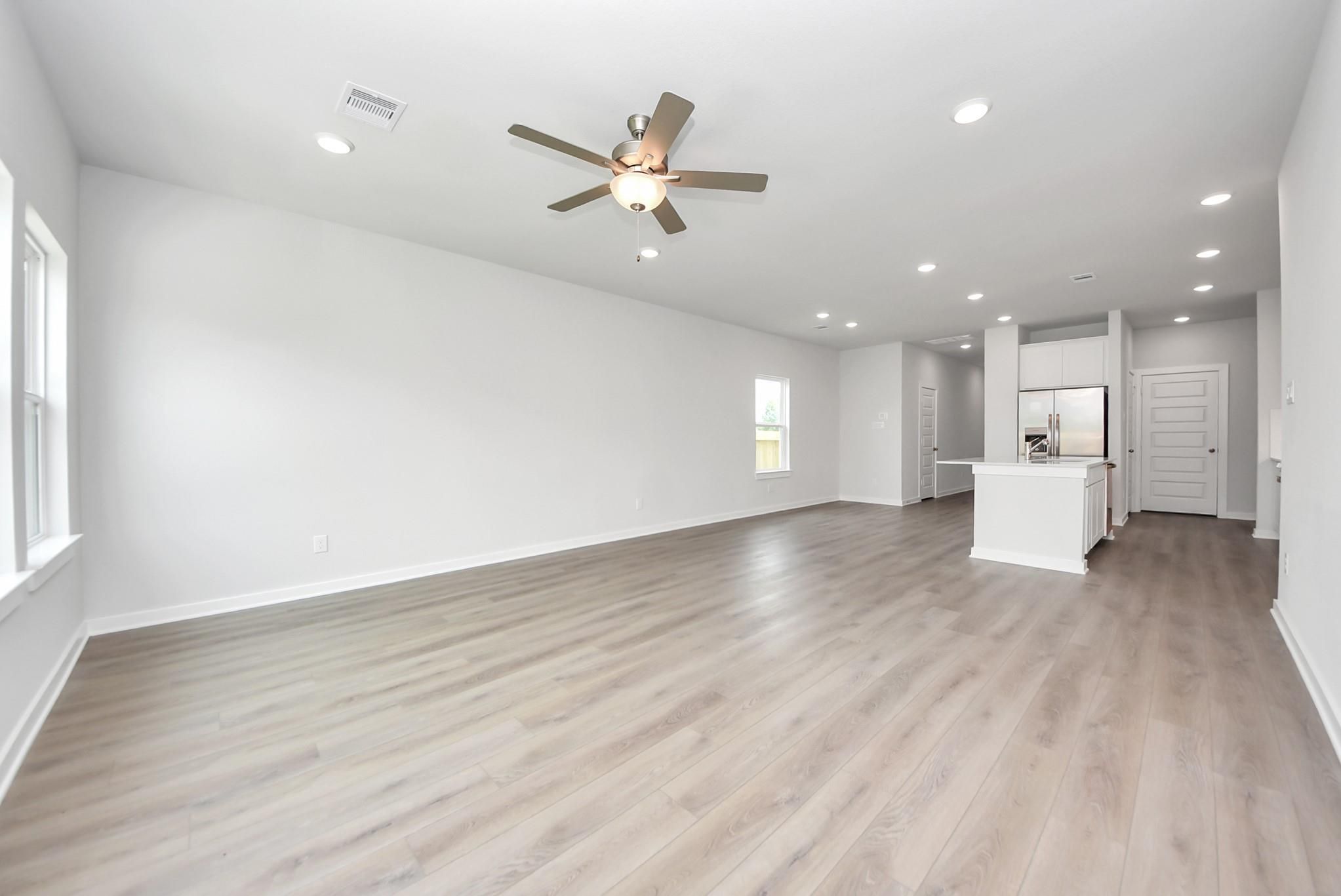 Open-concept living room with light wood floors in The Blanco E floor plan at The Villages at WestPointe, Dayton, Texas.