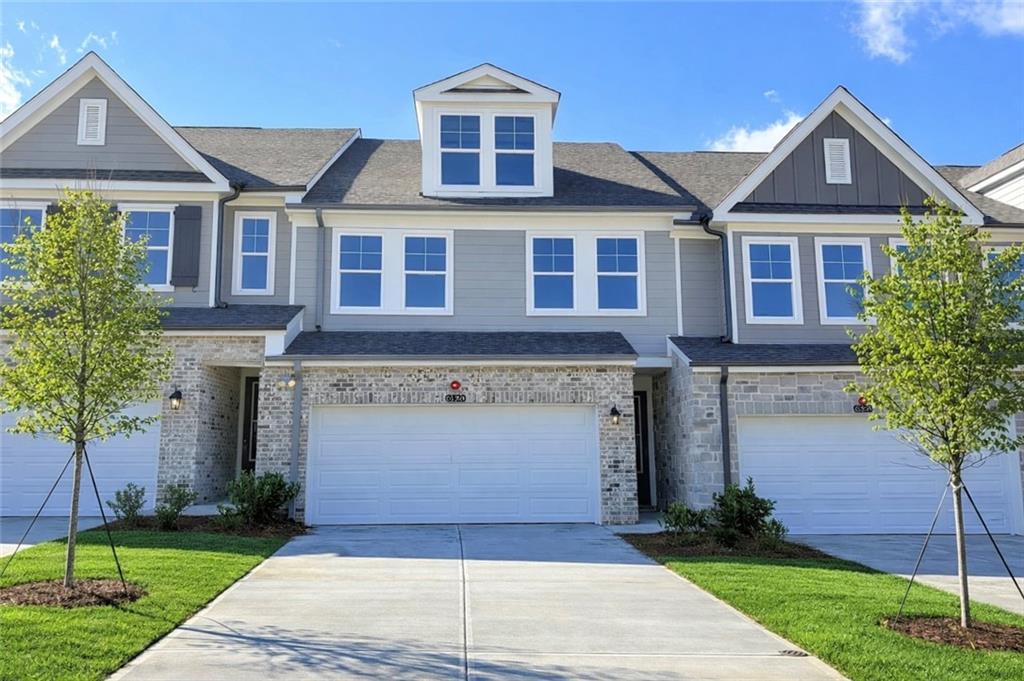 Two-story townhome exterior with gray siding, brick accents, 2-car garage, and driveway in Hemingway, Cumming, Georgia - Davidson Homes The Wake E