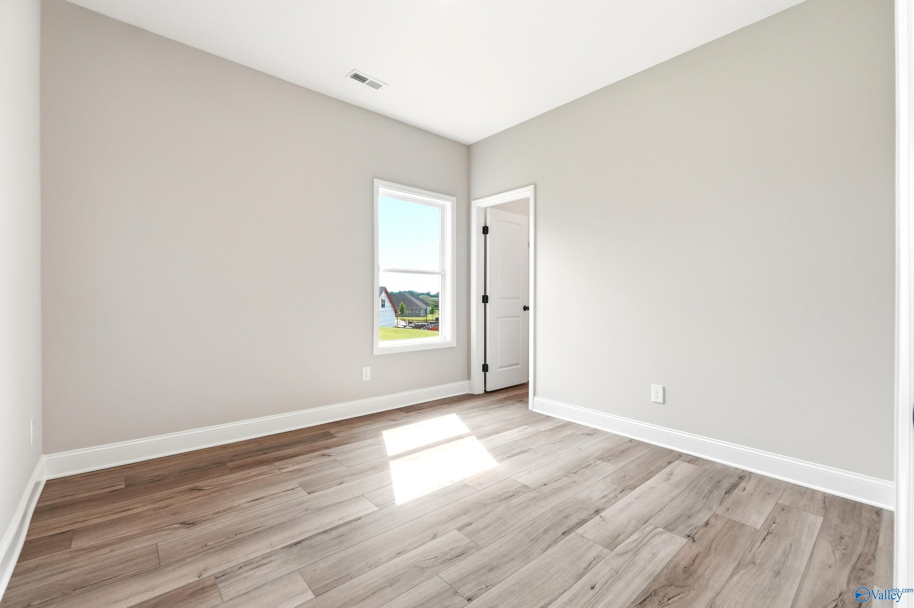 Bright bedroom with wood-look flooring in The Daphne D floor plan by Davidson Homes in Creekside, Harvest, Alabama.