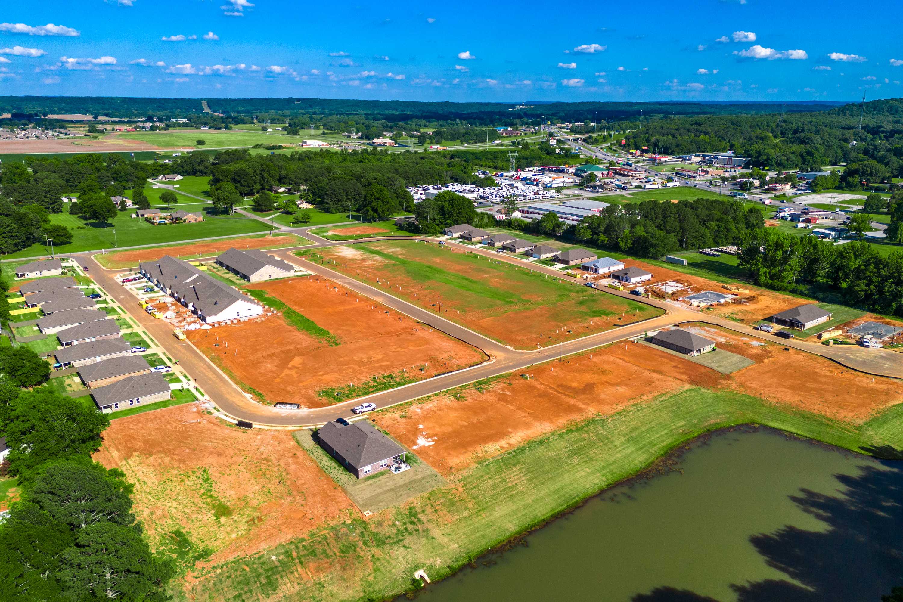Aerial view of Hollon Meadow new homes community in Decatur Alabama with construction sites red dirt lots and pond