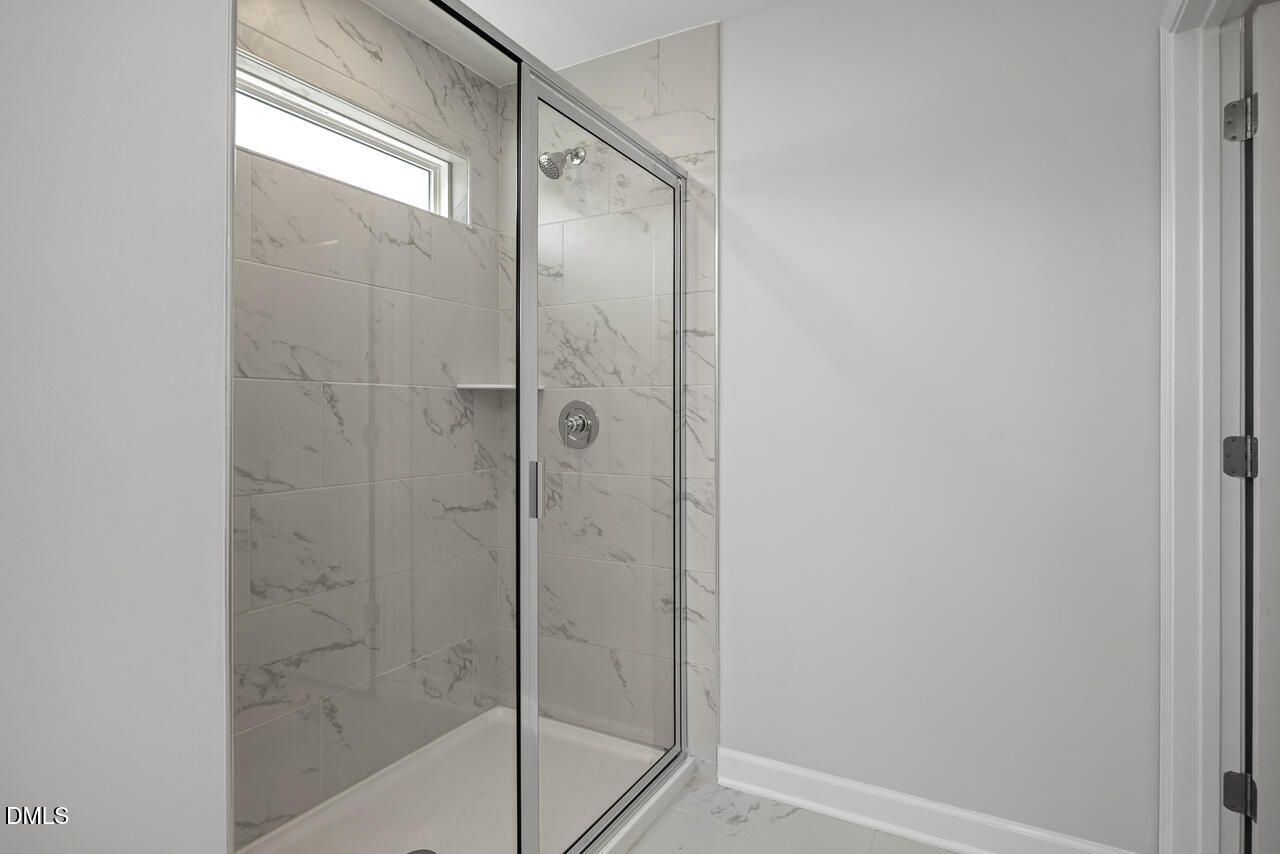 Modern walk-in shower with marble-look tile in The Adalynn A floor plan at Gregory Village, Lillington, North Carolina.