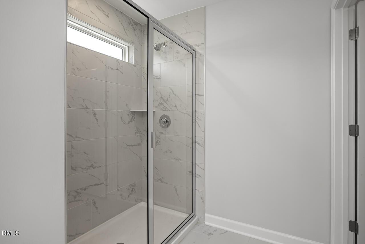 Modern walk-in shower with marble-look tile in The Adalynn A floor plan at Gregory Village, Lillington, North Carolina.